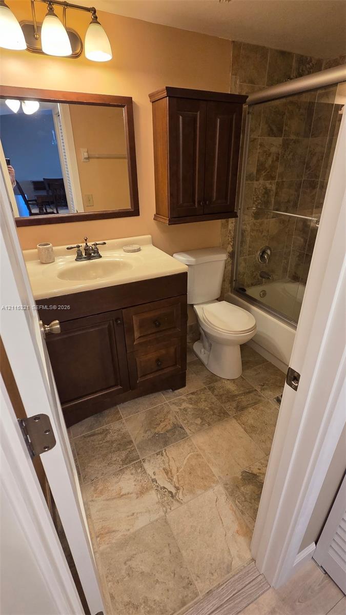 Bathroom featuring a dark wood vanity with a stone countertop, a built-in wall cabinet, tiled flooring, and a shower-tub combination with tile surround