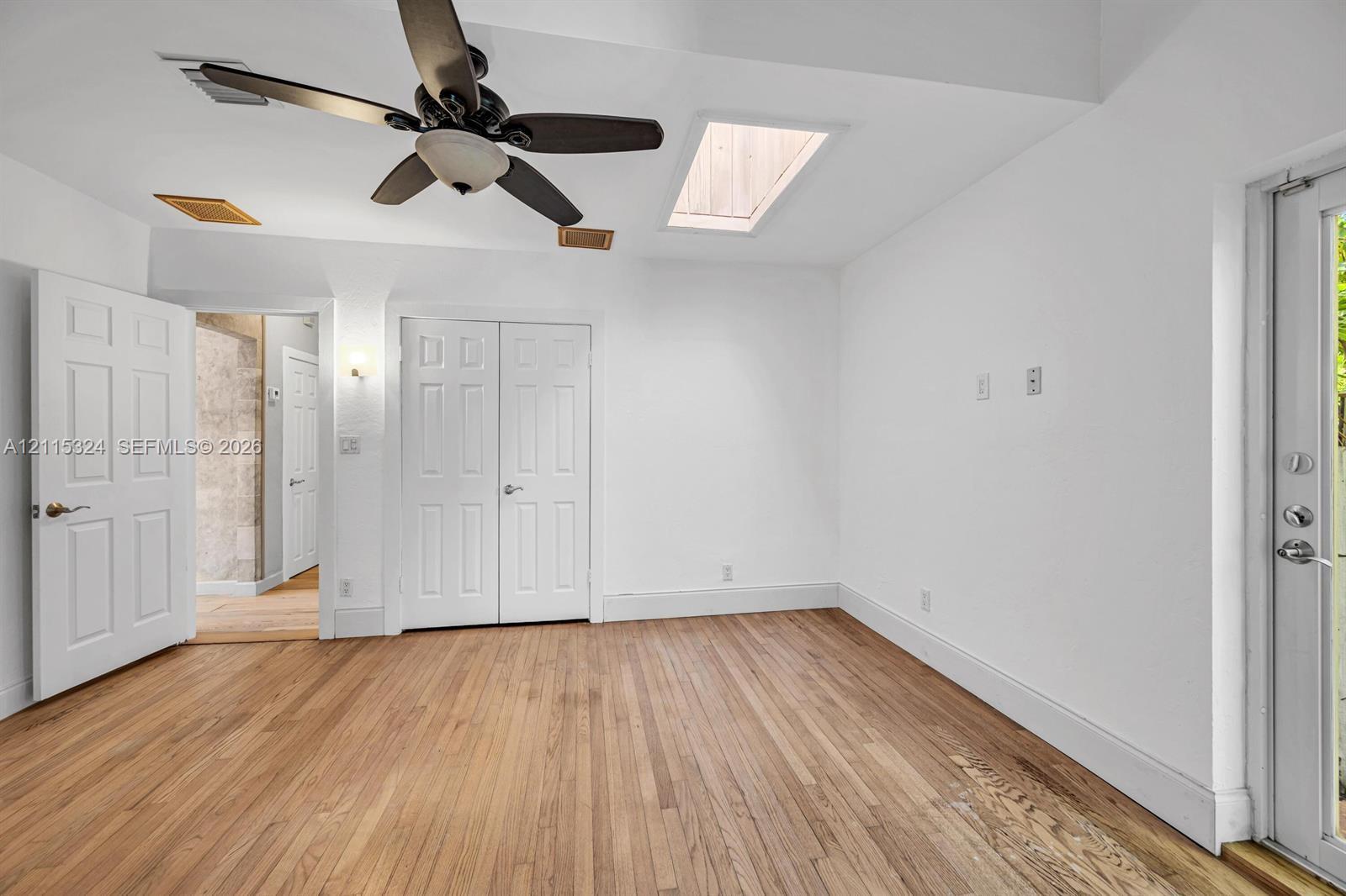 Wood-finish flooring, ceiling fan with integrated lighting, skylight, and multi-panel interior doors