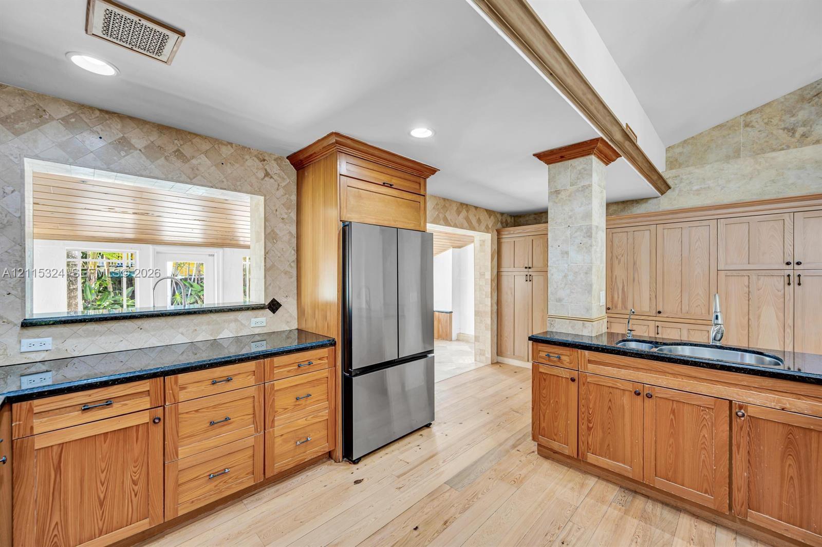 Kitchen featuring wood cabinetry, stone tile backsplashes, dark stone countertops, recessed lighting, and wood-finish flooring