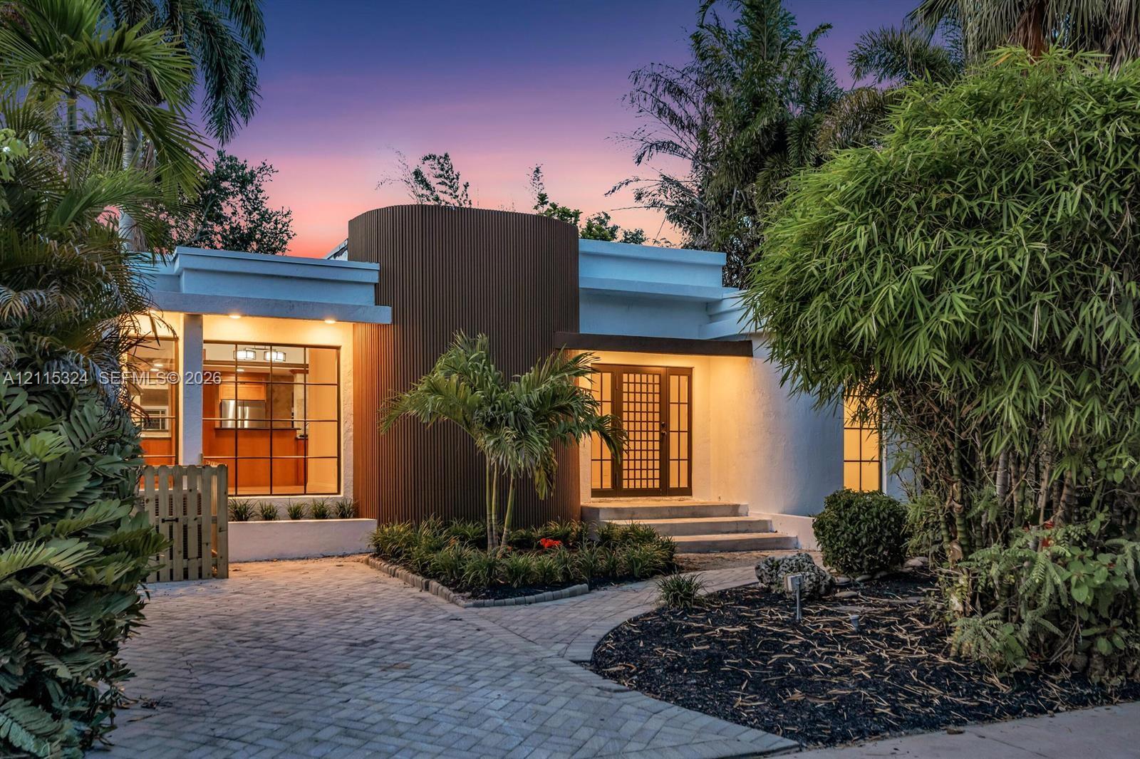 Mid-century modern exterior featuring vertical wood-slat siding, a geometric grid-pattern front door, large-format grid windows, and a paved brick driveway