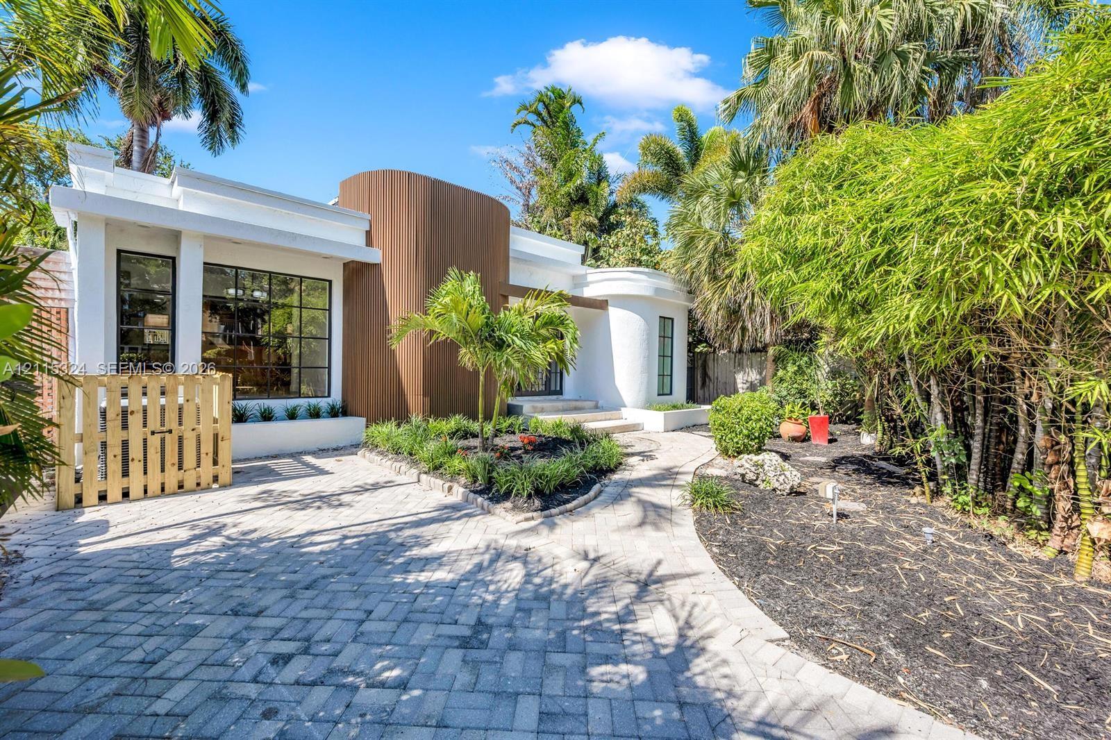 Contemporary exterior featuring curved architectural details, vertical wood-finish siding, white stucco facade, large multi-pane windows, and a paved stone driveway Contemporary exterior featuring curved architectural details, vertical wood-finish siding, white stucco facade, large multi-pane windows, and a paved stone driveway