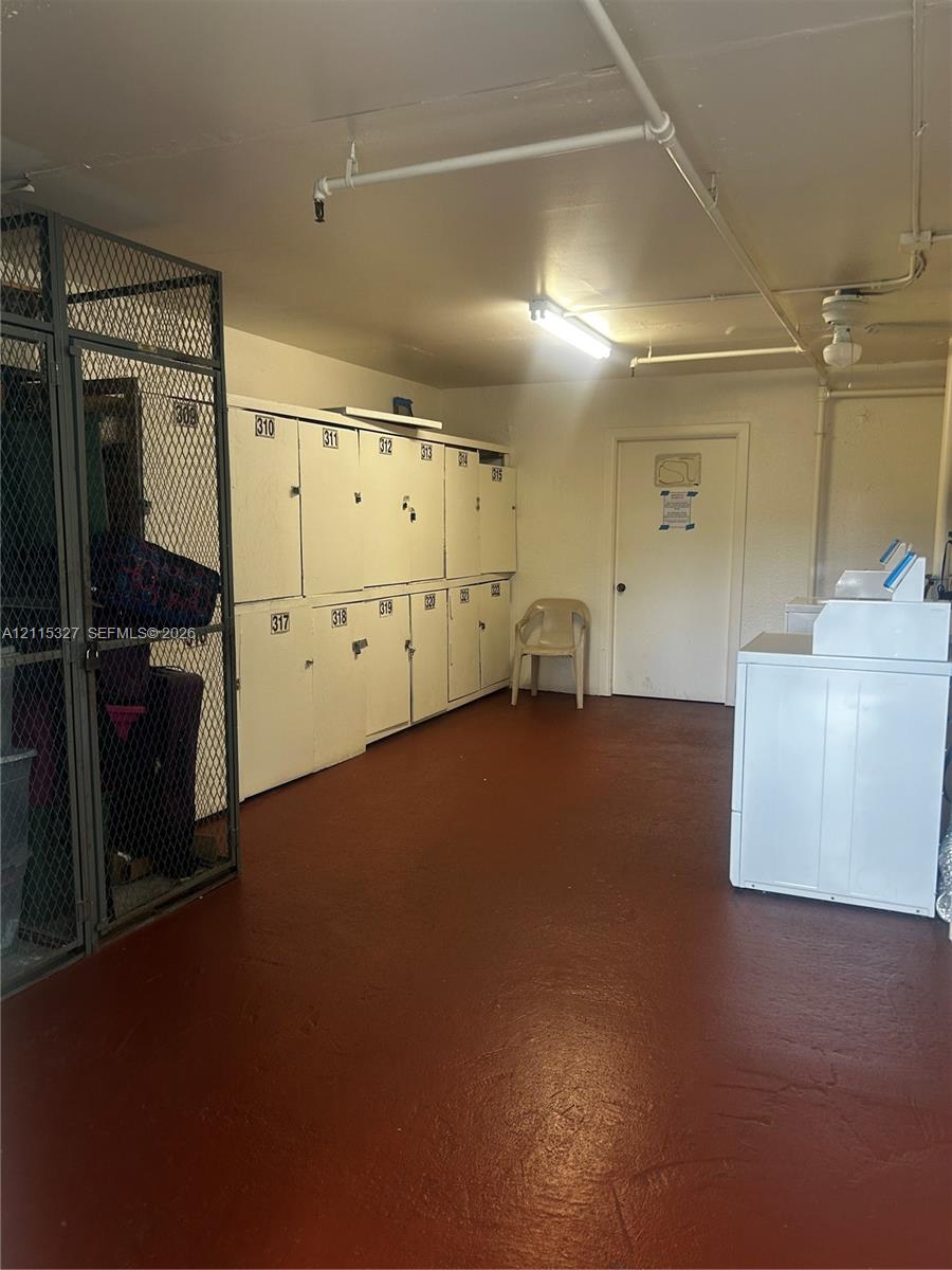 Utility room featuring metal storage lockers, a secure wire mesh enclosure, painted concrete flooring, and an integrated fire sprinkler system