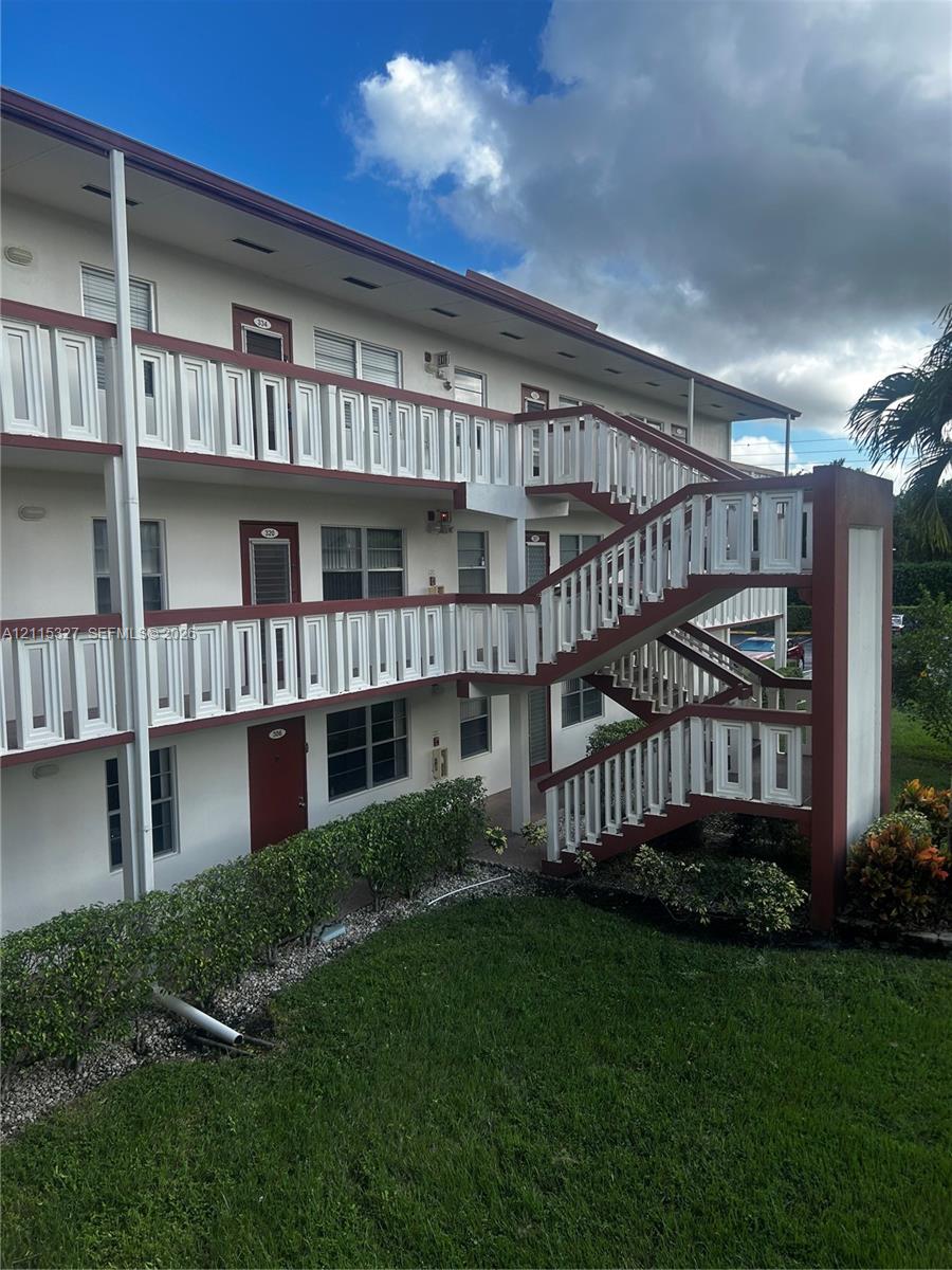 Multi-story exterior featuring white stucco siding, contrasting trim, white decorative railings, and an integrated outdoor staircase