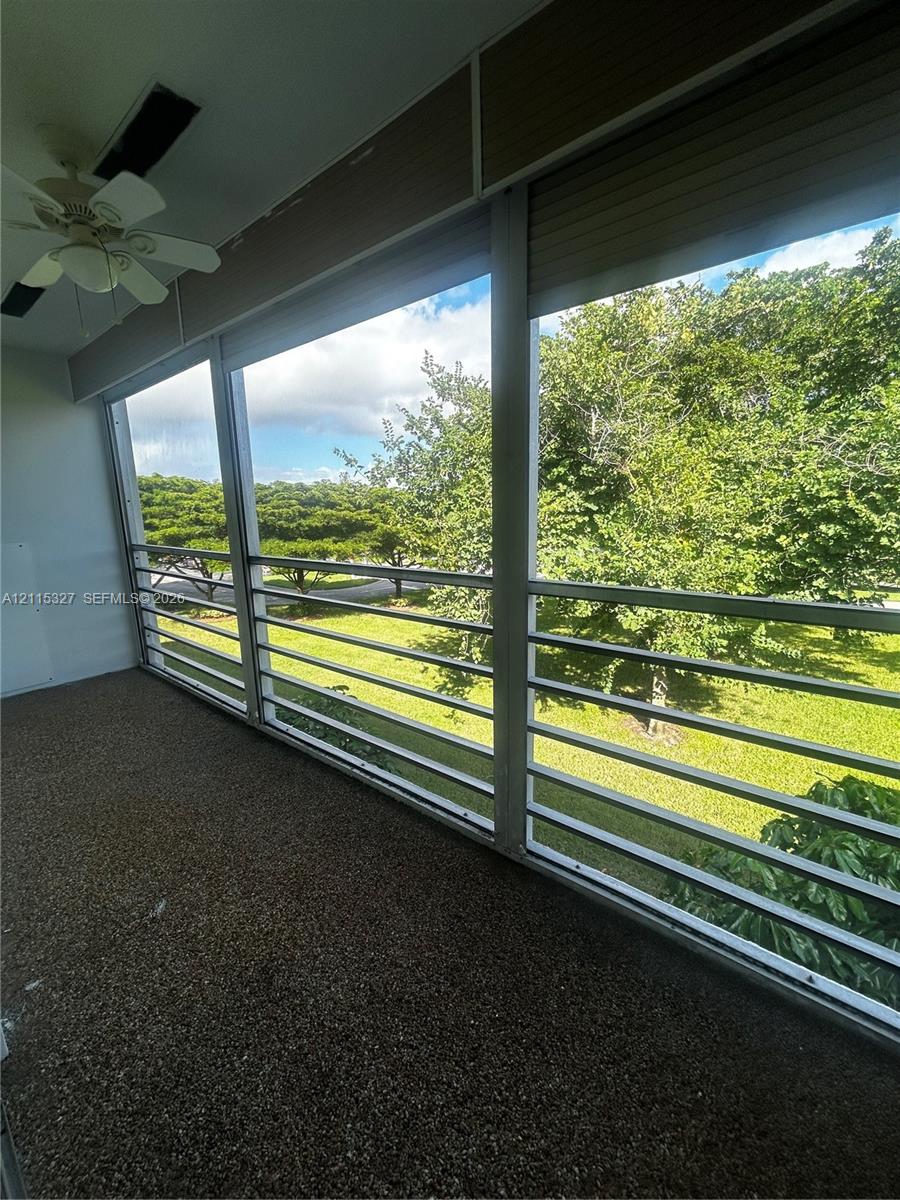 Covered balcony featuring aggregate flooring, horizontal metal railing, integrated ceiling fan, and retractable exterior shades