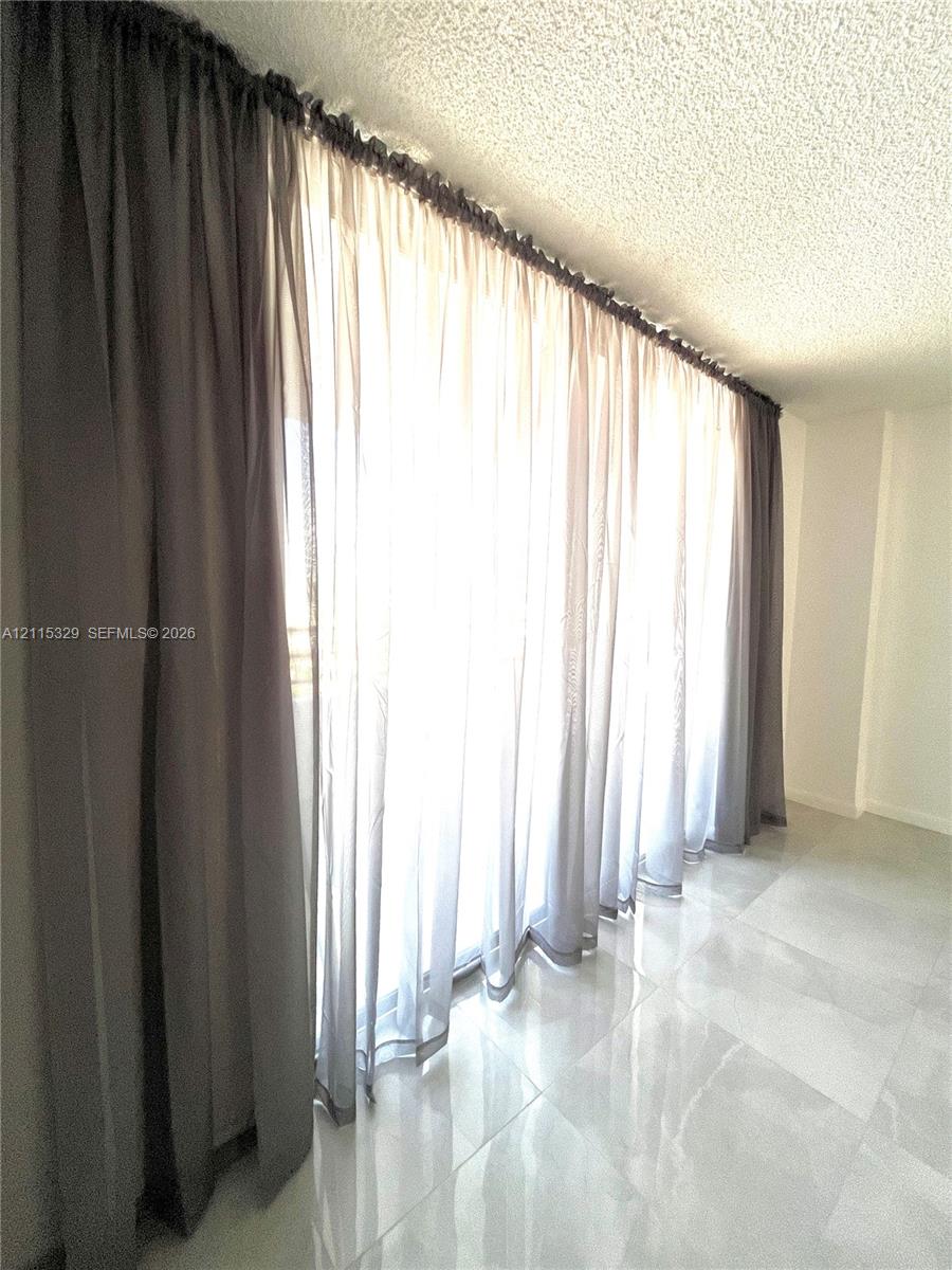 Large-format glass sliding door system with floor-to-ceiling profile and polished light-toned tile flooring