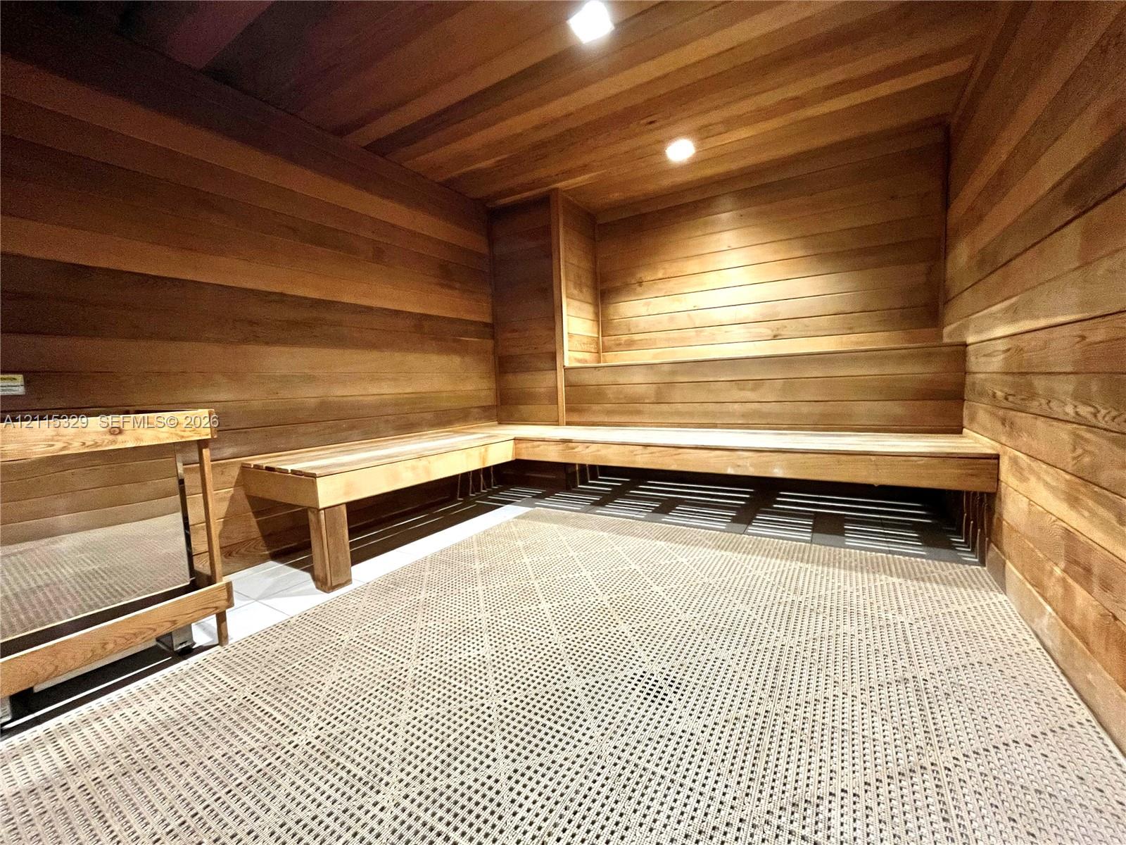 Sauna featuring horizontal wood paneling on the walls and ceiling, tiered built-in wood benches, and recessed lighting