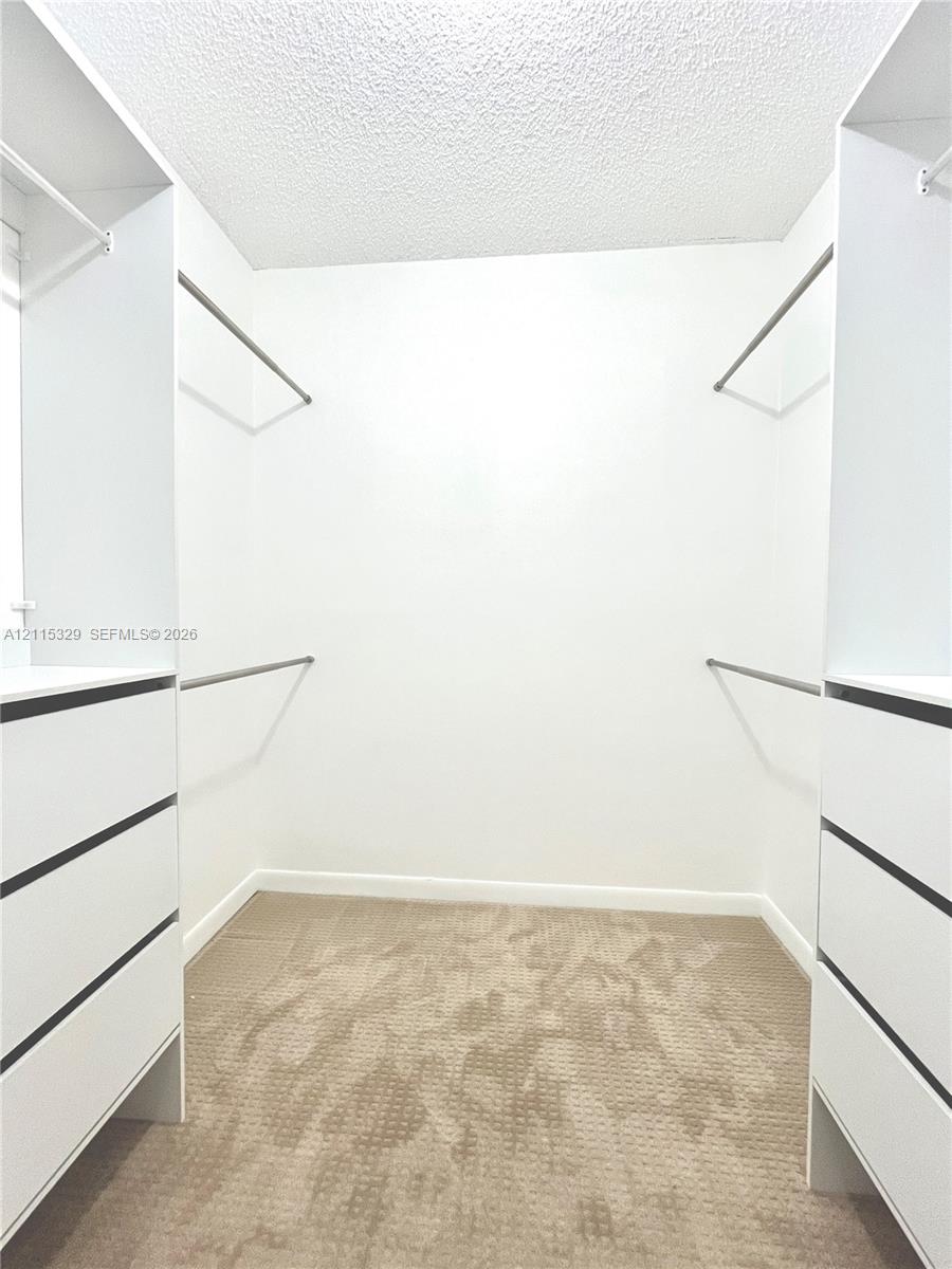 Walk-in closet featuring white built-in cabinetry, multiple drawers, tiered clothing rods