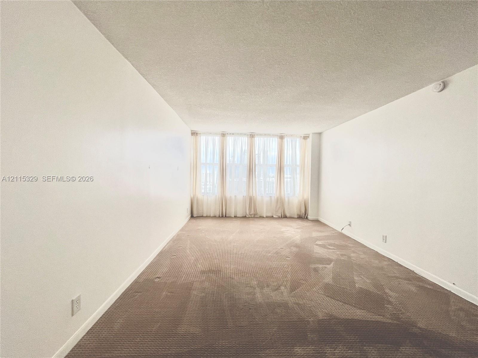 Neutral-toned carpeted flooring, textured ceiling, and floor-to-ceiling windows