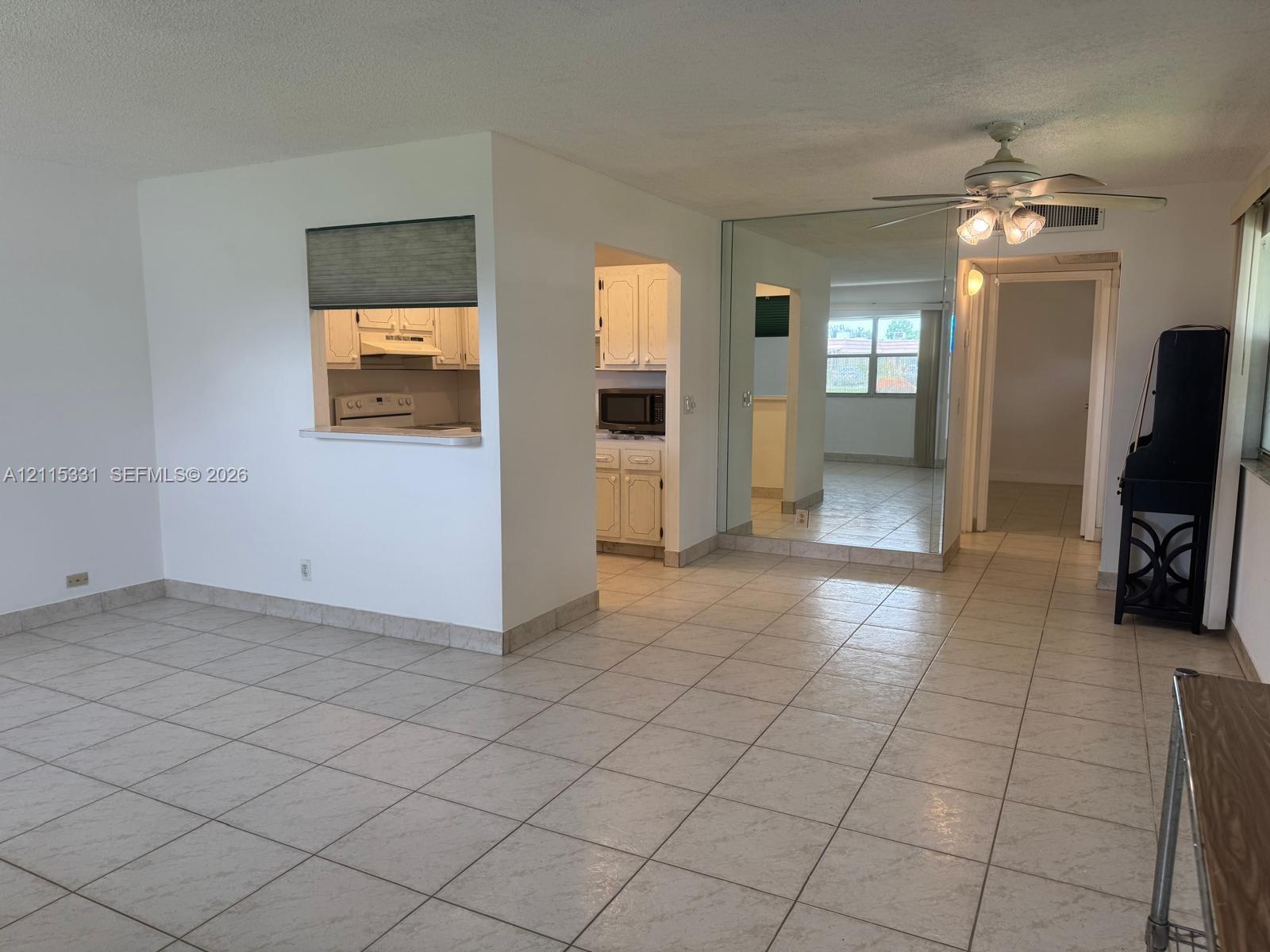 Ceramic tile flooring, mirrored wall paneling, ceiling-mounted light fixture with fan, and interior pass-through window with ledge Ceramic tile flooring, mirrored wall paneling, ceiling-mounted light fixture with fan, and interior pass-through window with ledge
