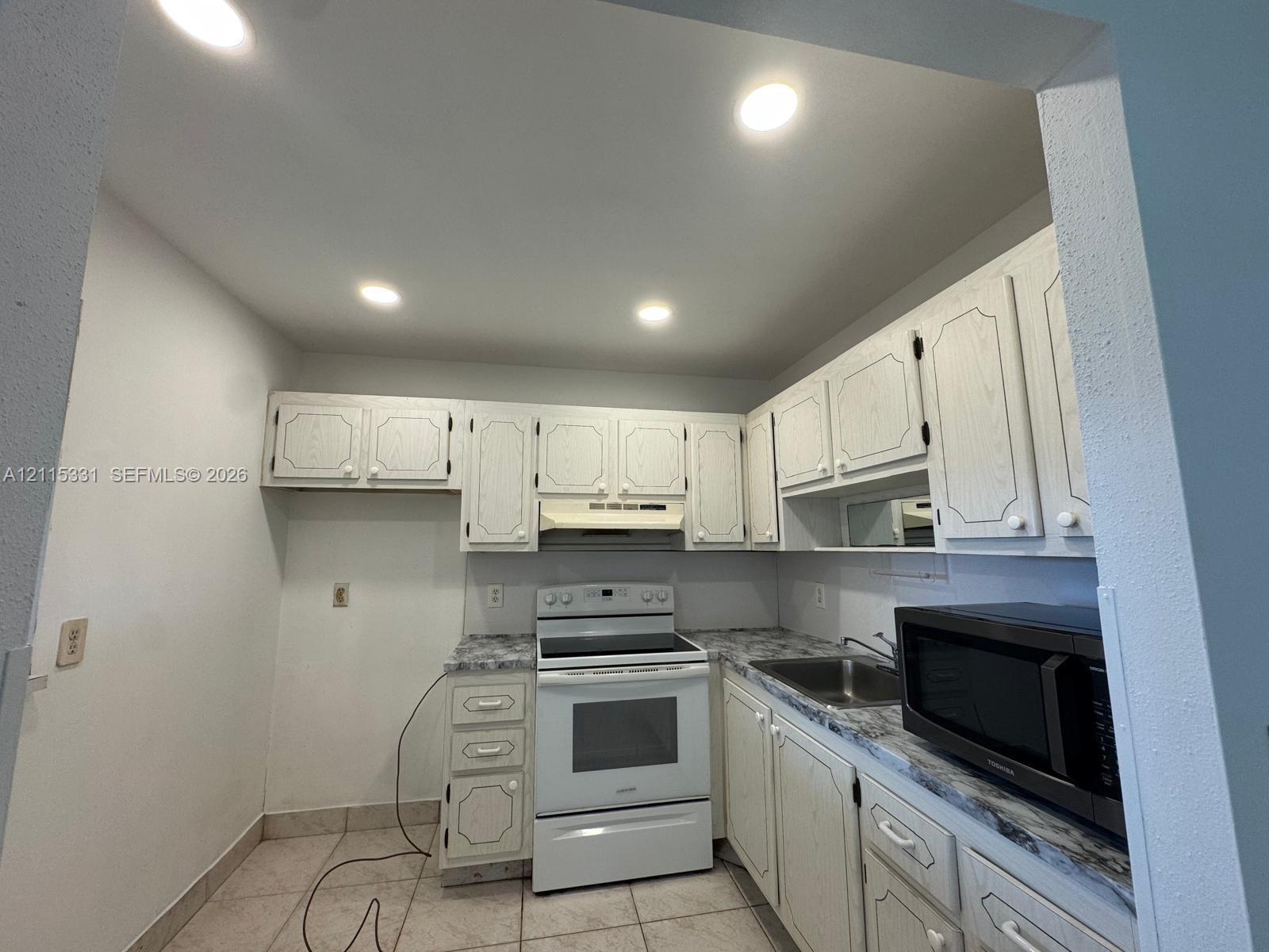 Kitchen featuring white cabinetry, stone-finish countertops, stainless steel sink, recessed lighting, and white electric range