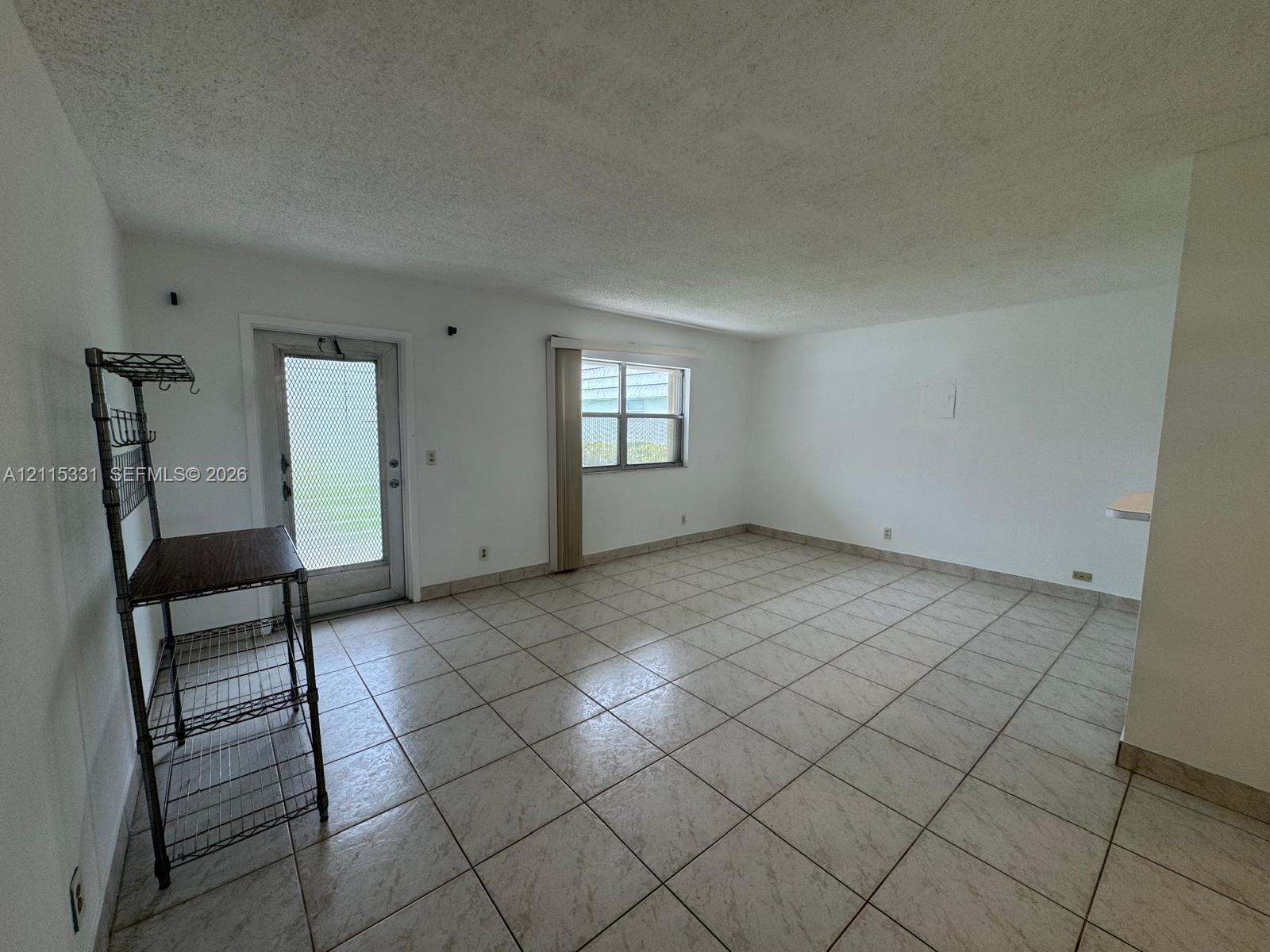 Neutral-toned ceramic tile flooring, textured ceiling finish, exterior door with textured glass inset, and double-pane window Neutral-toned ceramic tile flooring, textured ceiling finish, exterior door with textured glass inset, and double-pane window