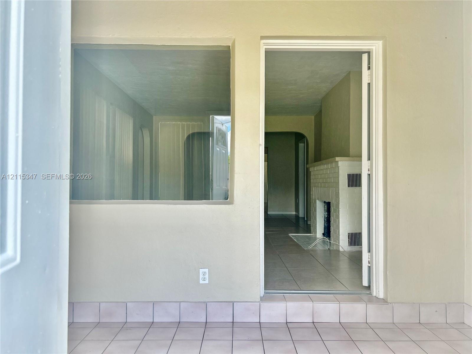 Tiled flooring, large picture window, and interior fireplace with a brick surround