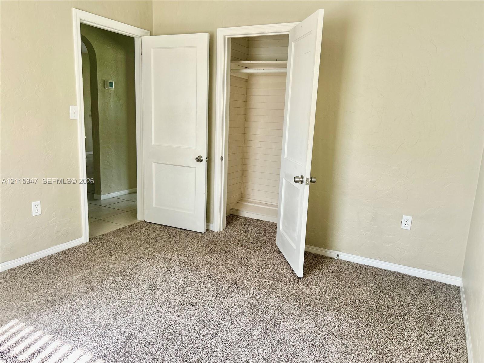 Textured wall finishes, neutral carpeting, and a built-in closet with integrated shelving
