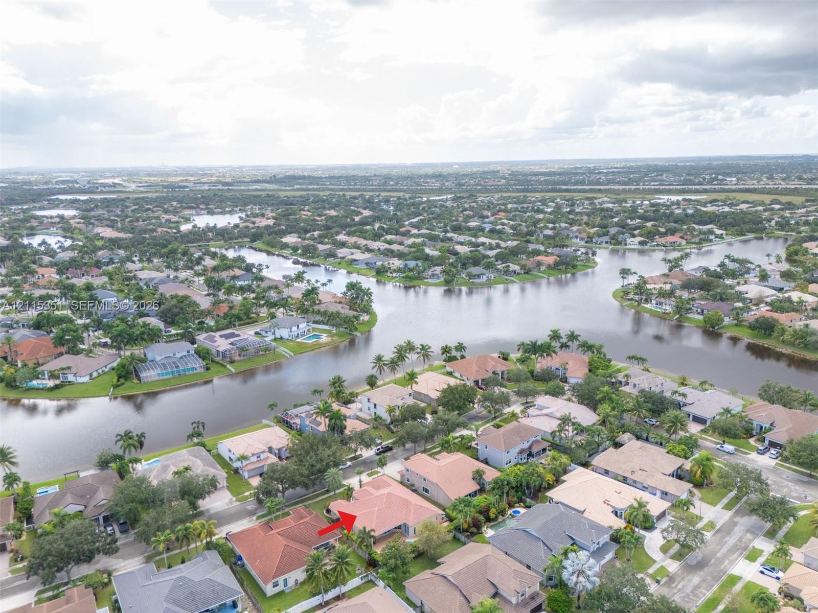 Aerial perspective of a residential property featuring a tiled hip roof and a landscaped lot situated on a canal