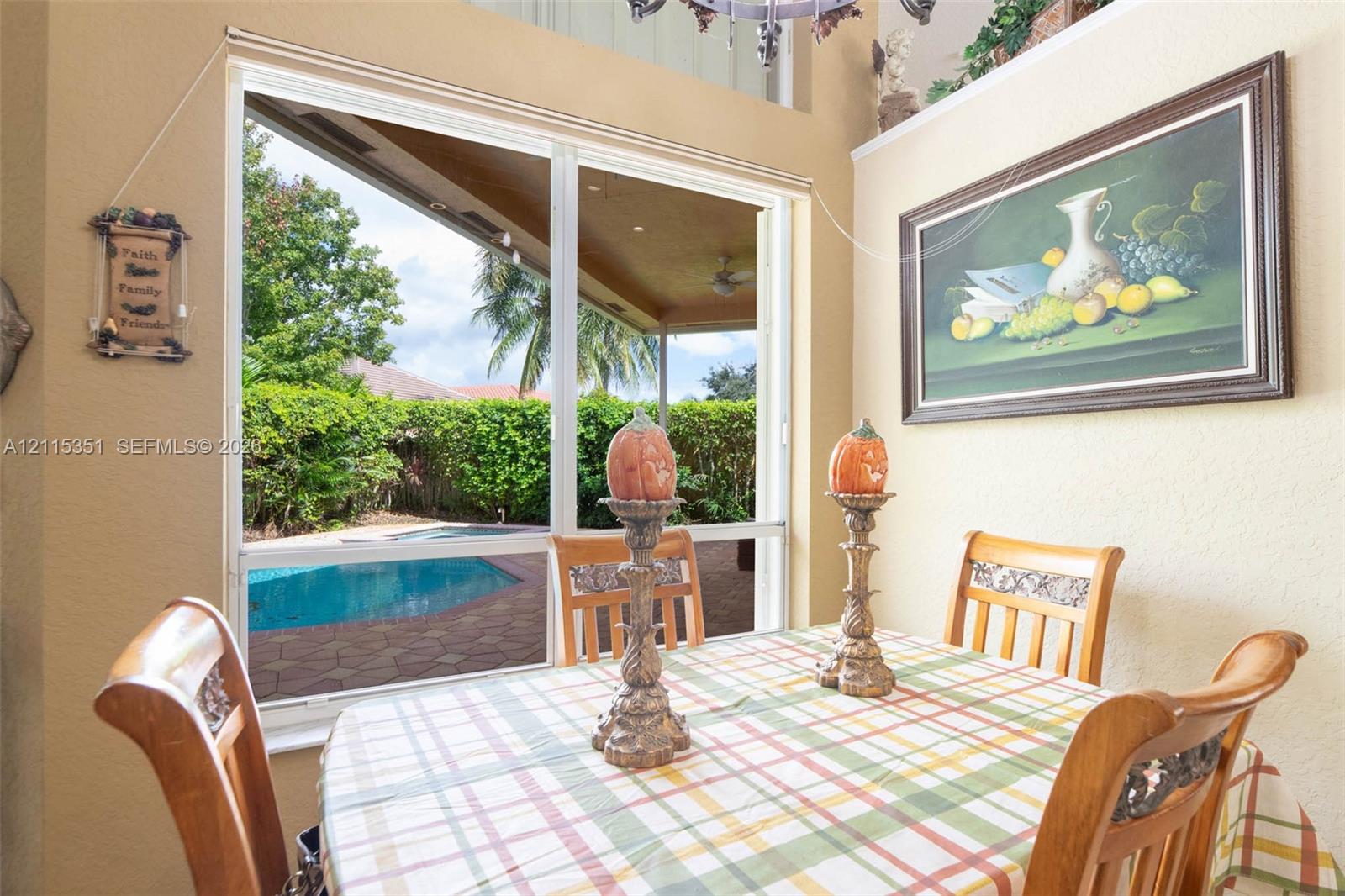 Large sliding glass doors providing access to a paved patio, swimming pool, and screened lanai