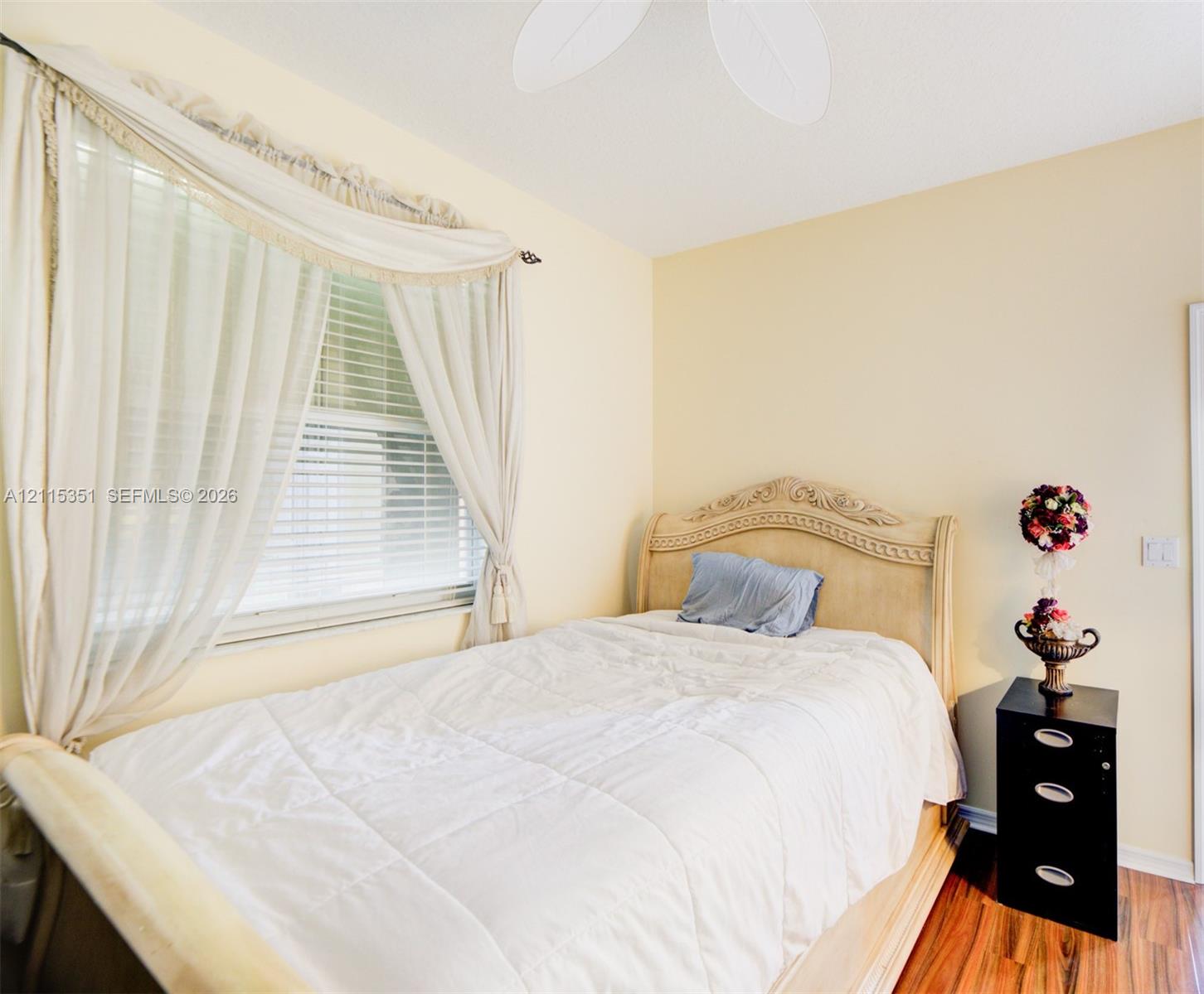 Room featuring wood-finish flooring, a ceiling fan, and a window with horizontal blinds
