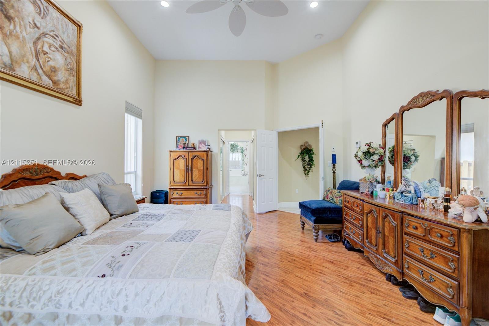 High-ceilinged room featuring wood-finish flooring, recessed lighting, a ceiling fan, and tall vertical windows