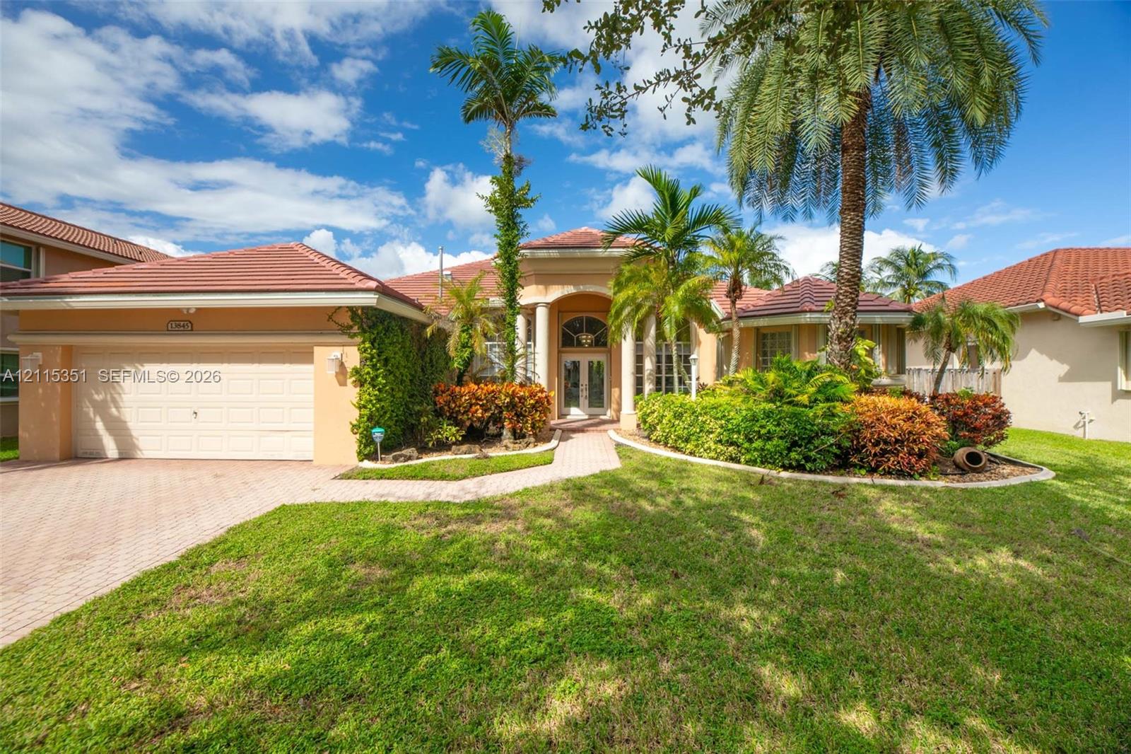 Stucco exterior featuring a clay tile roof, arched entryway with decorative columns, brick-paver driveway, and mature landscaping Stucco exterior featuring a clay tile roof, arched entryway with decorative columns, brick-paver driveway, and mature landscaping