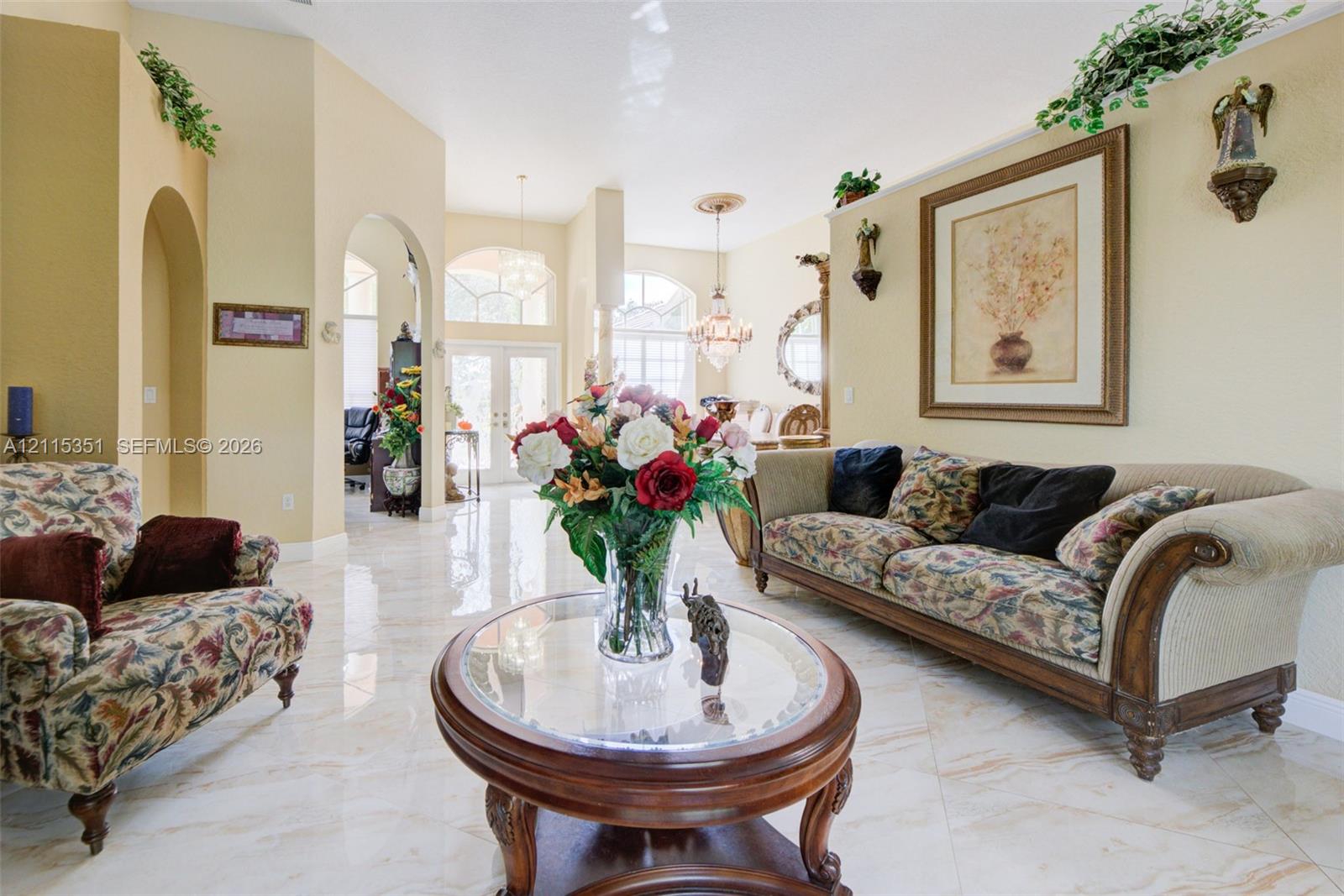 Open-concept interior featuring high ceilings, arched architectural entries, polished tile flooring, and multiple pendant light fixtures