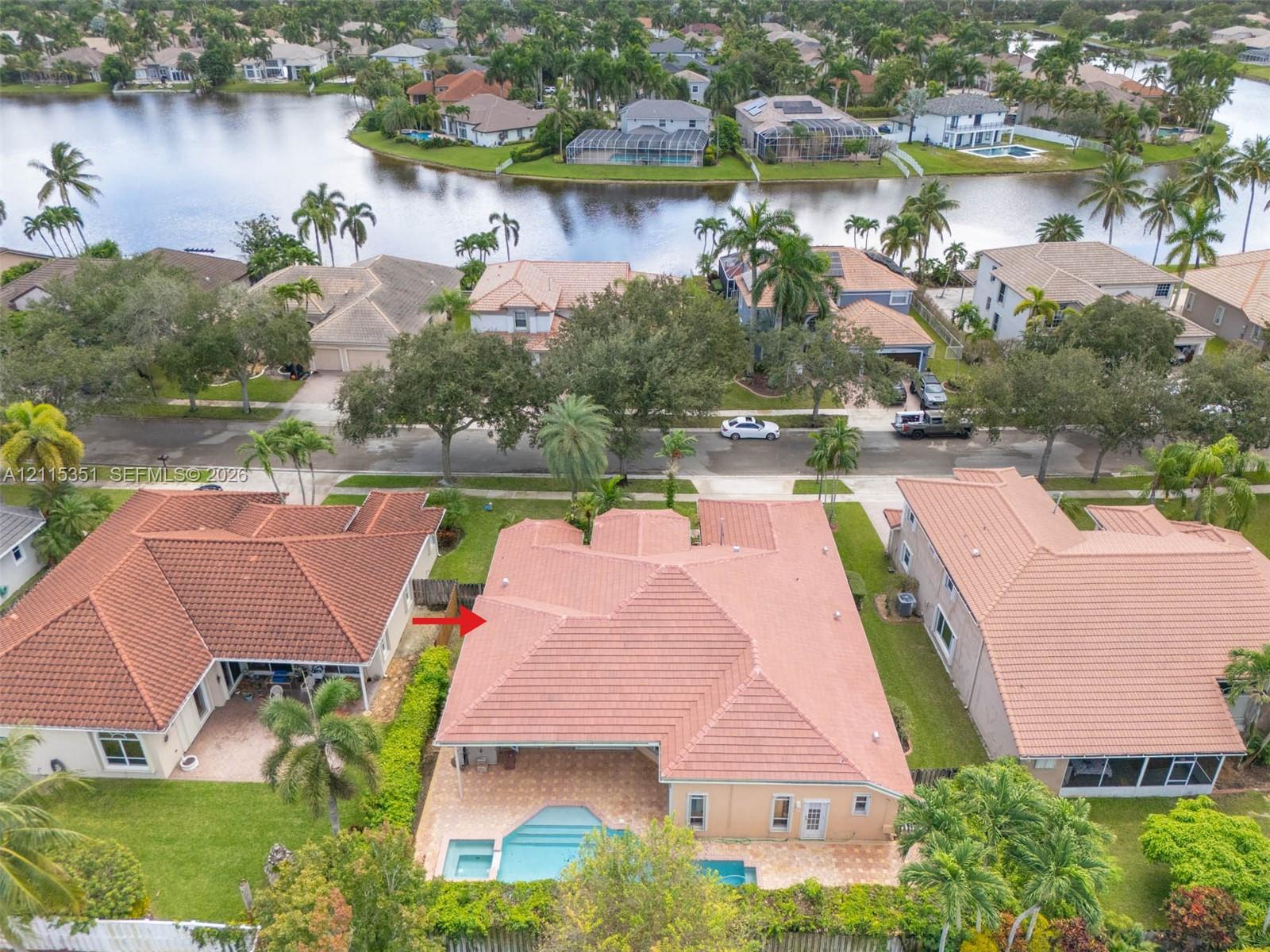 Aerial view featuring a tile roof, private swimming pool, paved rear patio, and water frontage Aerial view featuring a tile roof, private swimming pool, paved rear patio, and water frontage