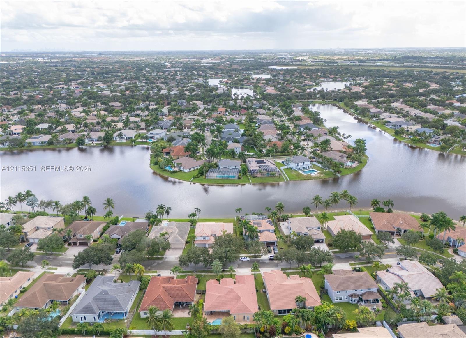 Aerial perspective featuring a waterfront residential community with mature landscaping and paved street grids