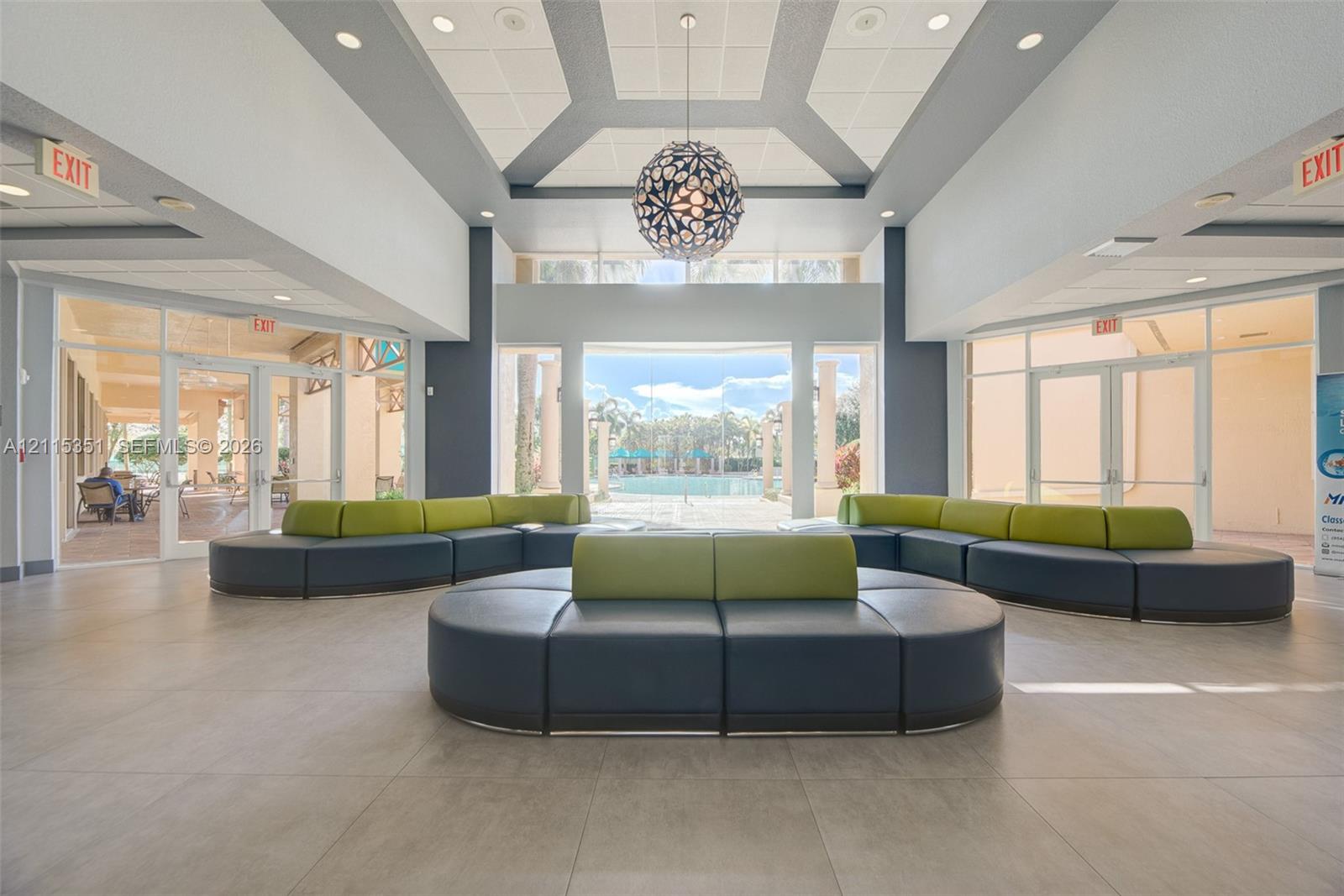Lobby featuring tile flooring, a recessed tray ceiling with accent lighting, a decorative spherical pendant light, and floor-to-ceiling glass wall panels