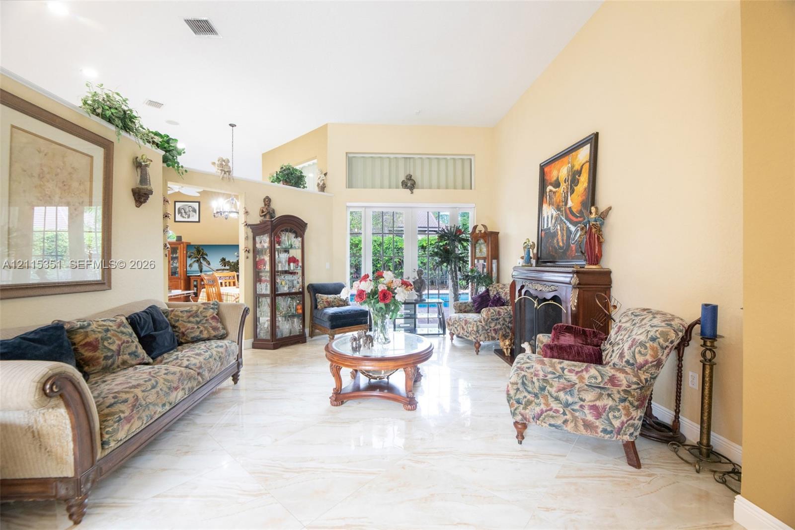 Living area featuring vaulted ceilings, polished tile flooring, a built-in fireplace, and expansive glass doors Living area featuring vaulted ceilings, polished tile flooring, a built-in fireplace, and expansive glass doors