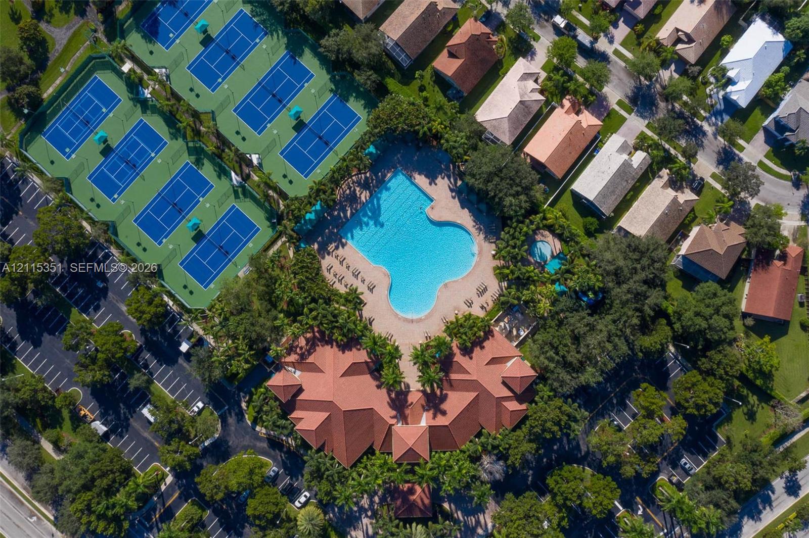Community amenities featuring a large outdoor swimming pool, a secondary circular pool, multiple tennis courts, and a central clubhouse with a terracotta-style tile roof