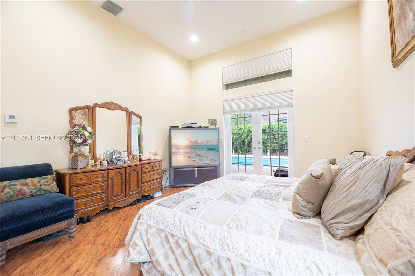 Vaulted ceilings, wood-finish flooring, transom window, and glass-paned double doors with outdoor pool access