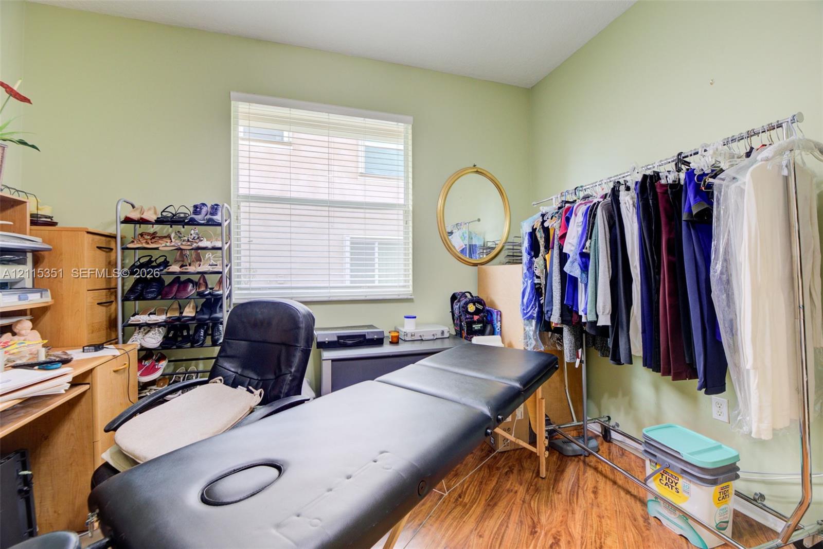 Room featuring wood-finish flooring and a central window with horizontal blinds