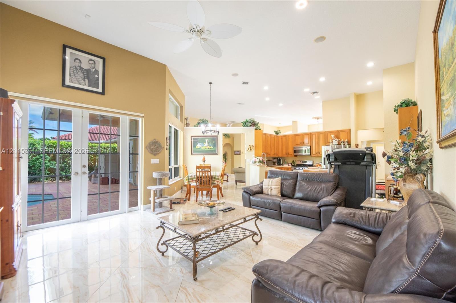 Vaulted ceilings with recessed lighting, tile flooring, and glass-paned double doors leading to a patio area