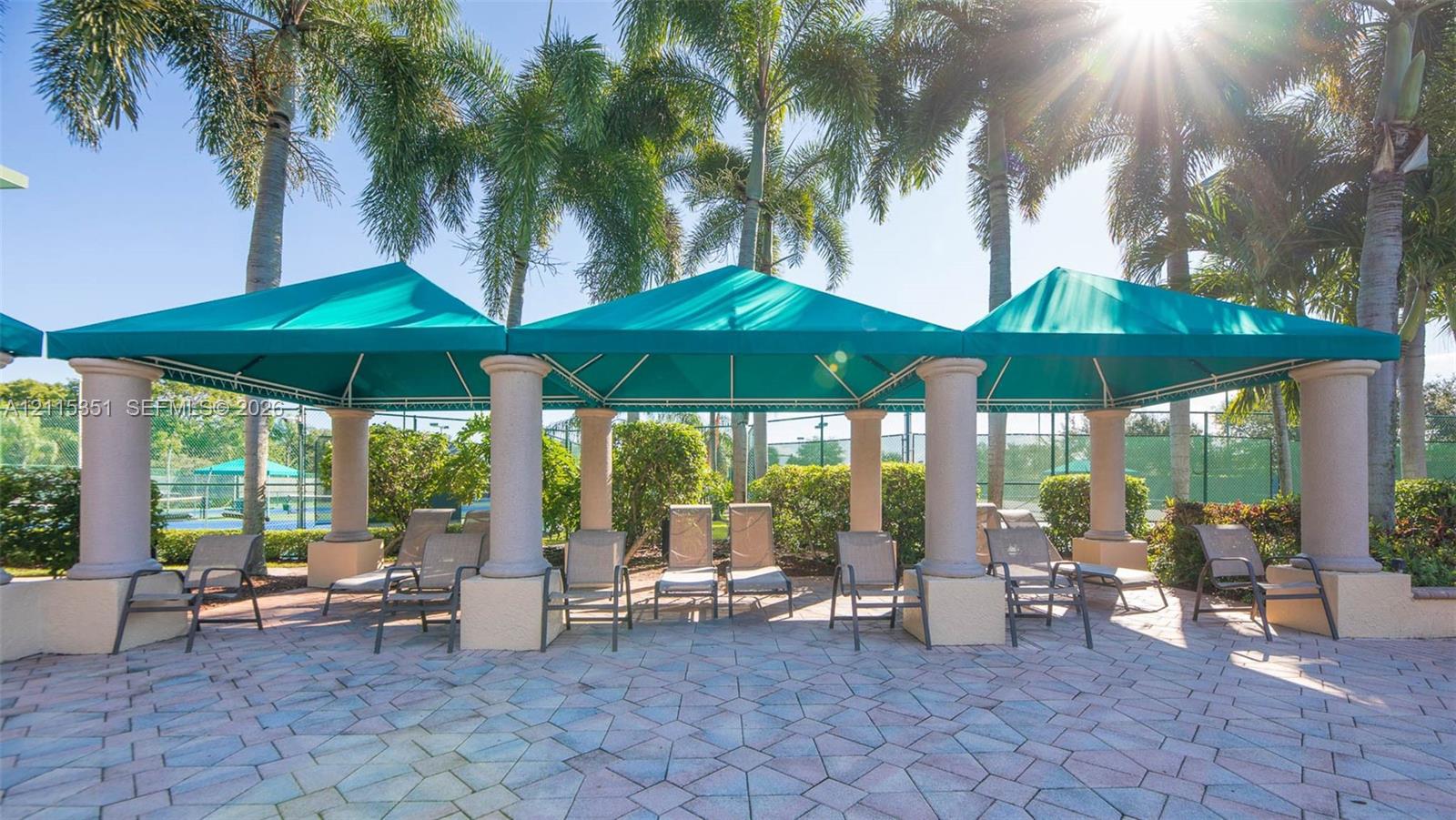 Outdoor covered lounge area featuring permanent fabric canopies, structural columns, and paved hardscaping