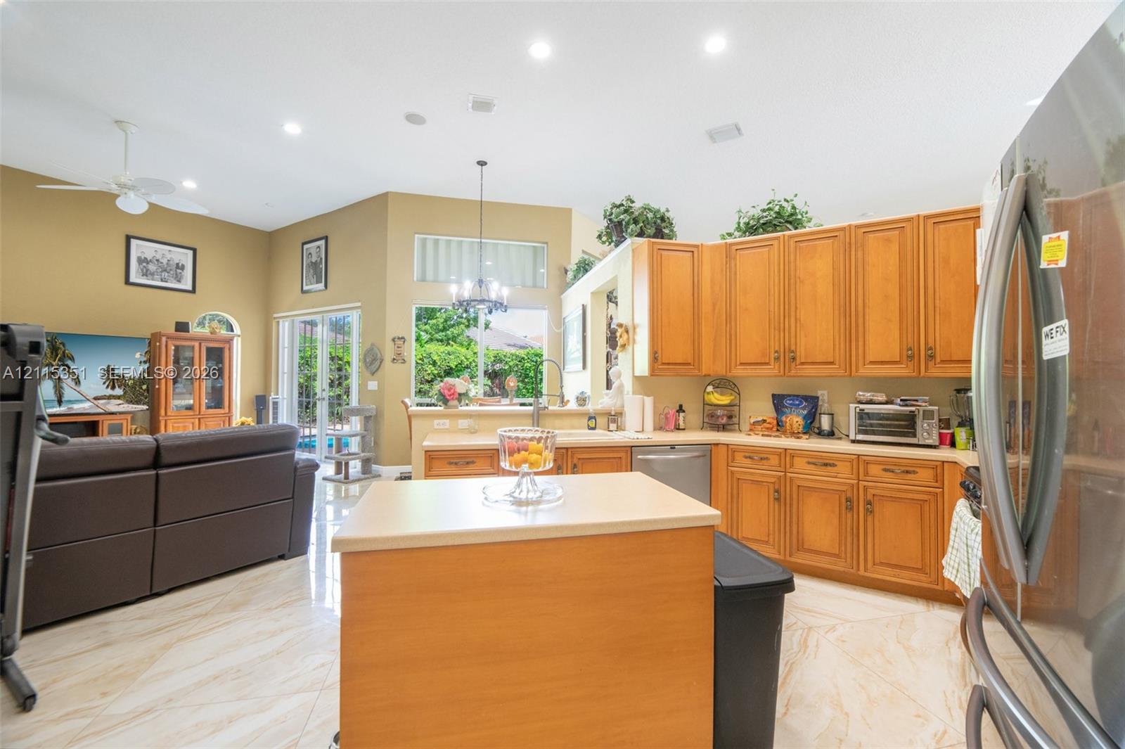 Open-concept kitchen featuring stained wood cabinetry, central island with countertop, recessed lighting, and tile flooring