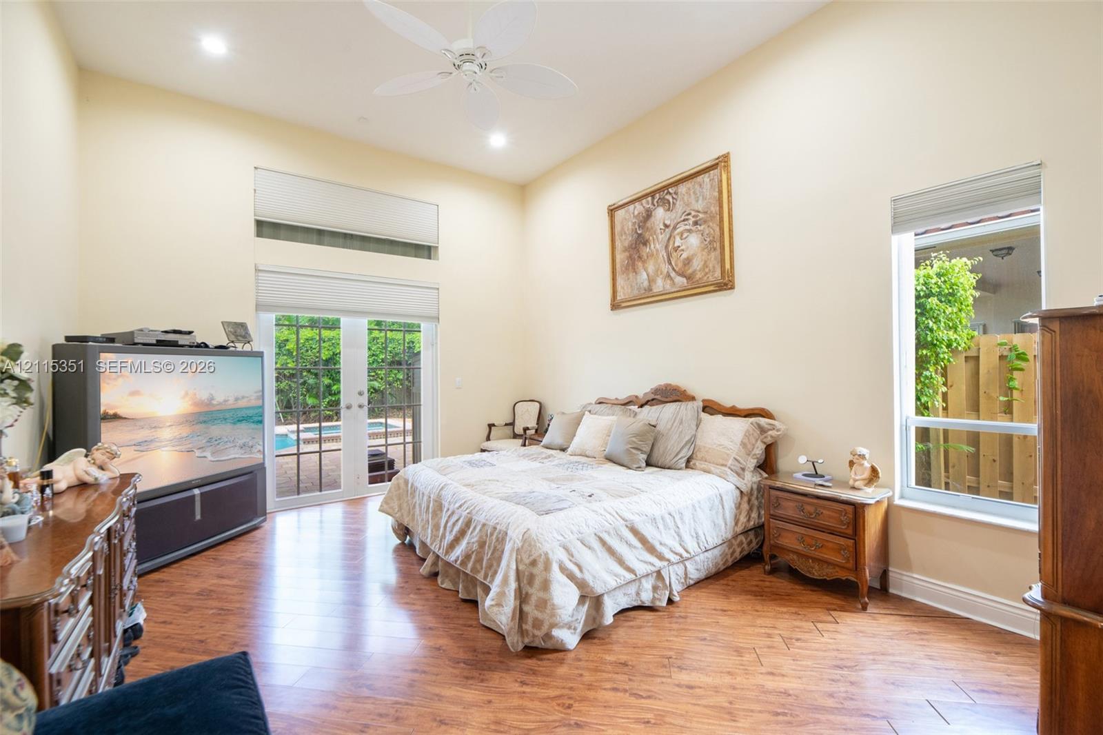 High-volume ceiling with recessed lighting and a central ceiling fan, wood-finish flooring in a herringbone pattern, tall transom windows, and full-glass paneled doors