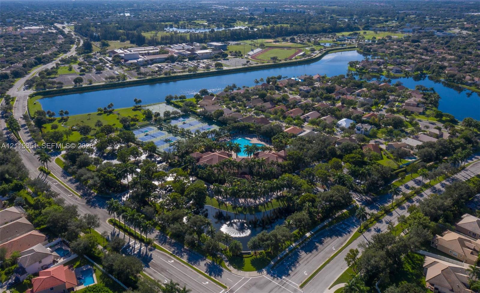 Aerial perspective of community featuring water frontage, tennis courts, an outdoor swimming pool, and mature landscaping
