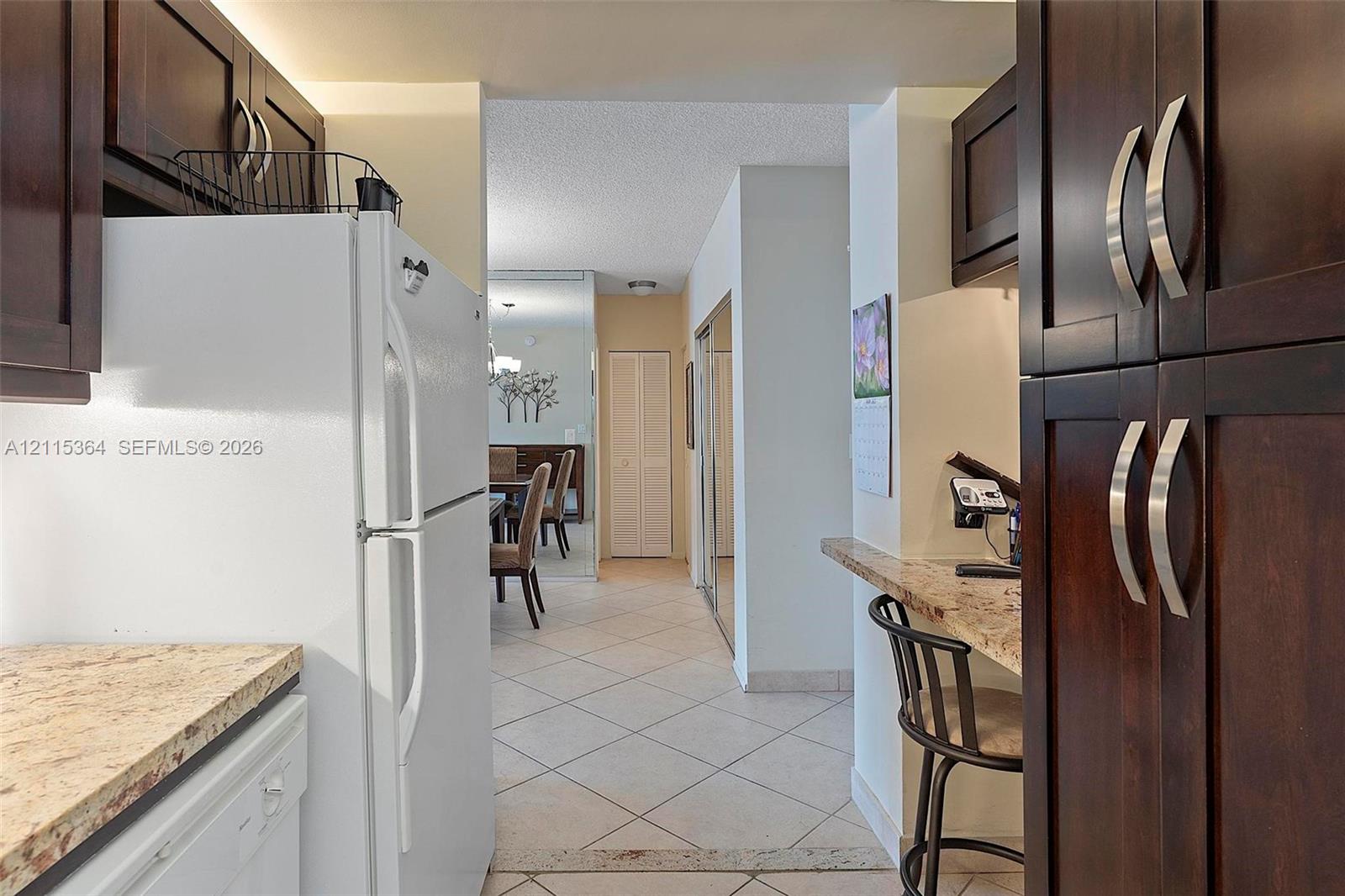 Dark wood cabinetry, stone-finish countertops, breakfast bar, and tile flooring
