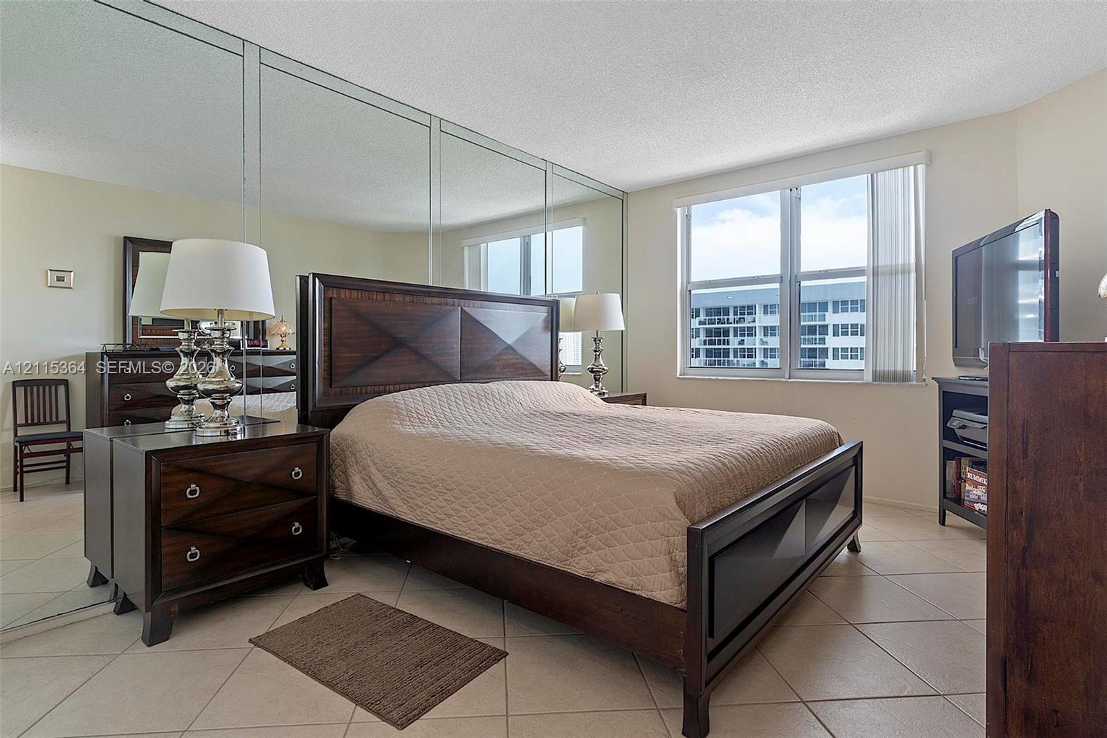 Wall-to-wall mirrored paneling, tile flooring, and large windows with integrated vertical blinds