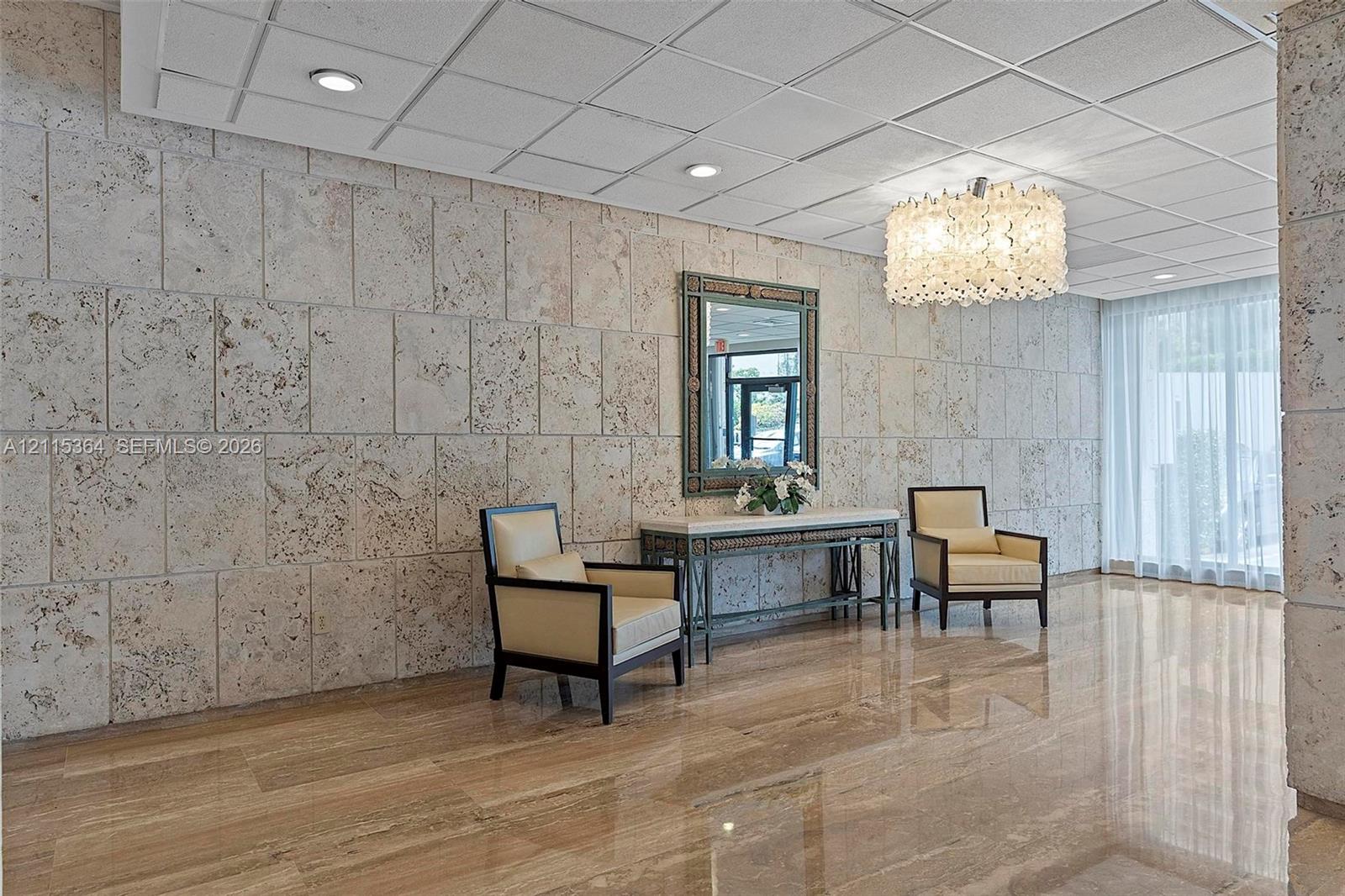 Polished stone flooring, textured stone wall cladding, recessed ceiling lighting, and a decorative chandelier