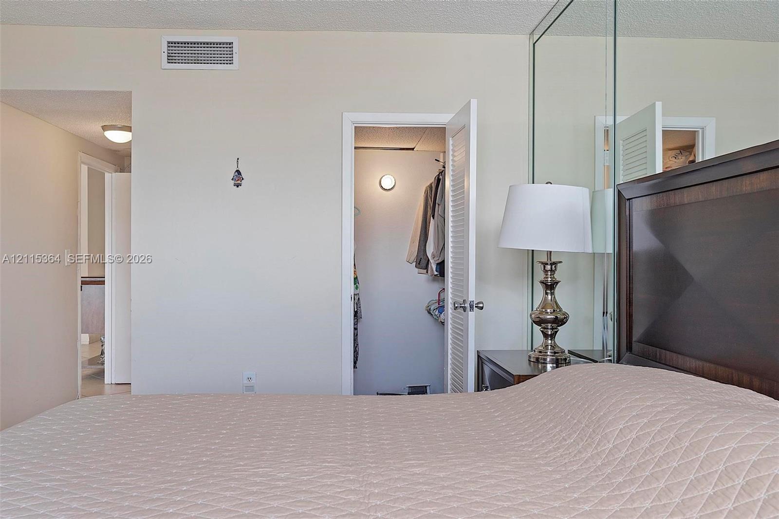 Full-wall mirrored accent, interior closet with louvered door, and recessed lighting