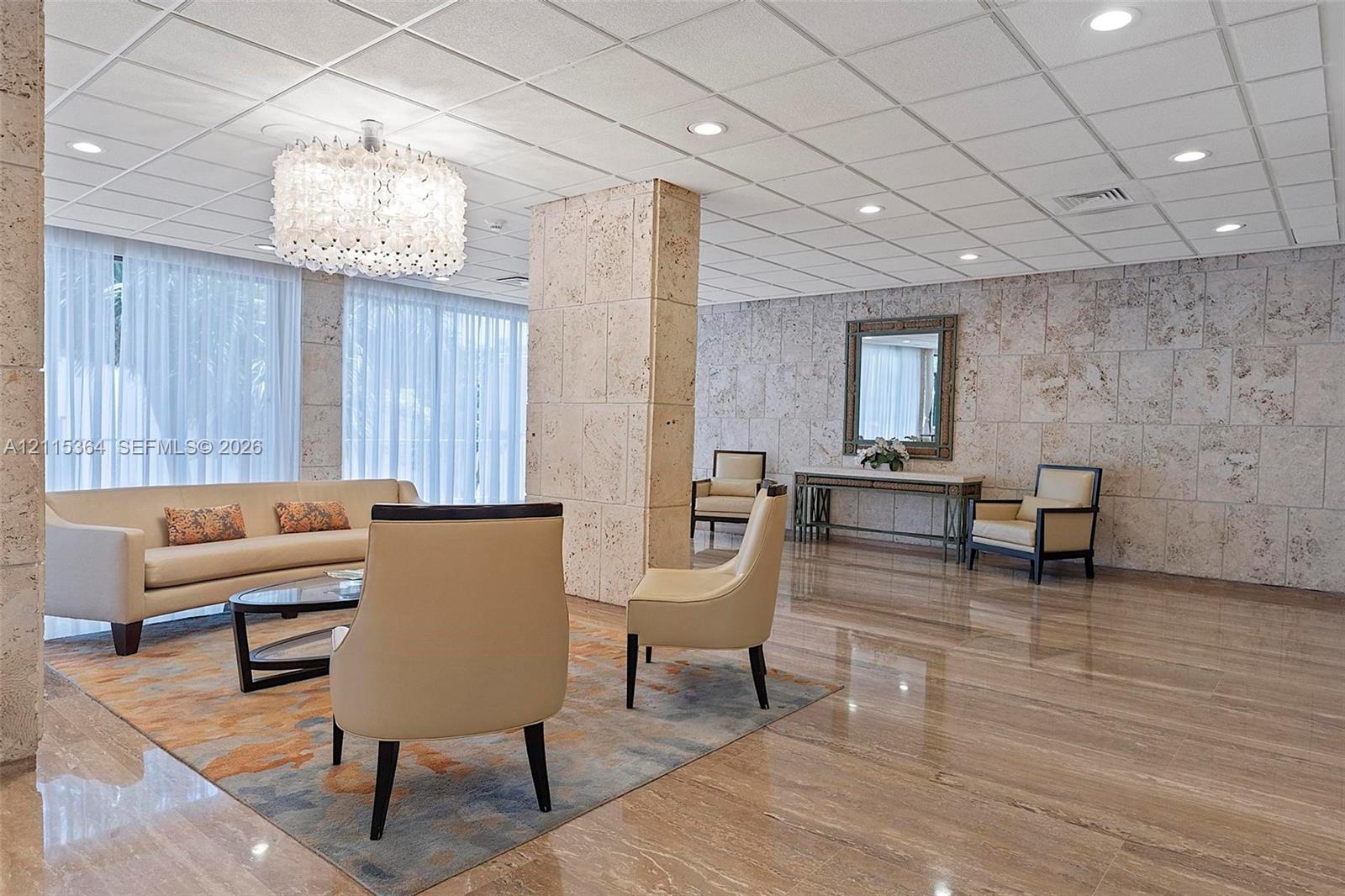 Polished stone flooring, textured stone wall cladding, a decorative chandelier, recessed ceiling lighting, and floor-to-ceiling sheer window coverings