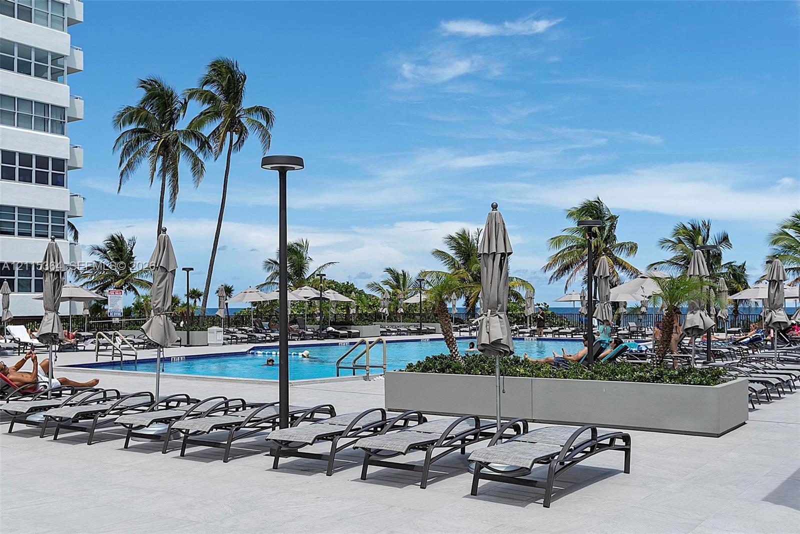 Swimming pool area featuring expansive stone-tile decking, integrated concrete planters, and exterior lighting fixtures