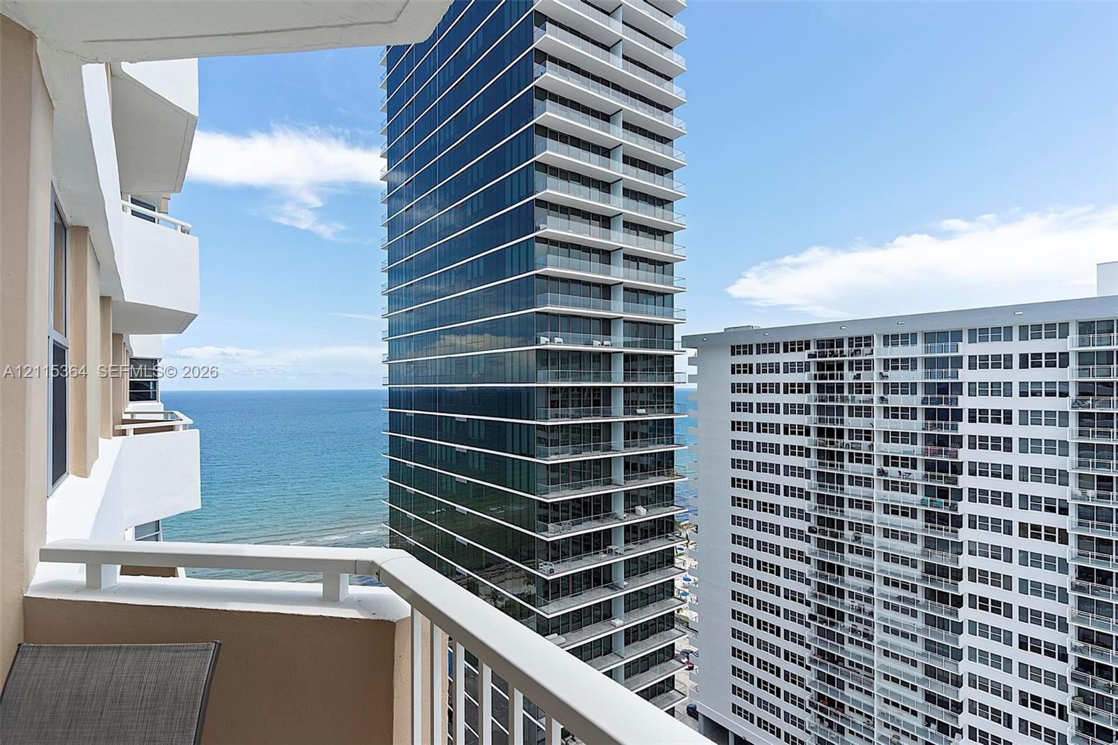 Private balcony featuring white metal railings and expansive coastal and urban horizon imagery
