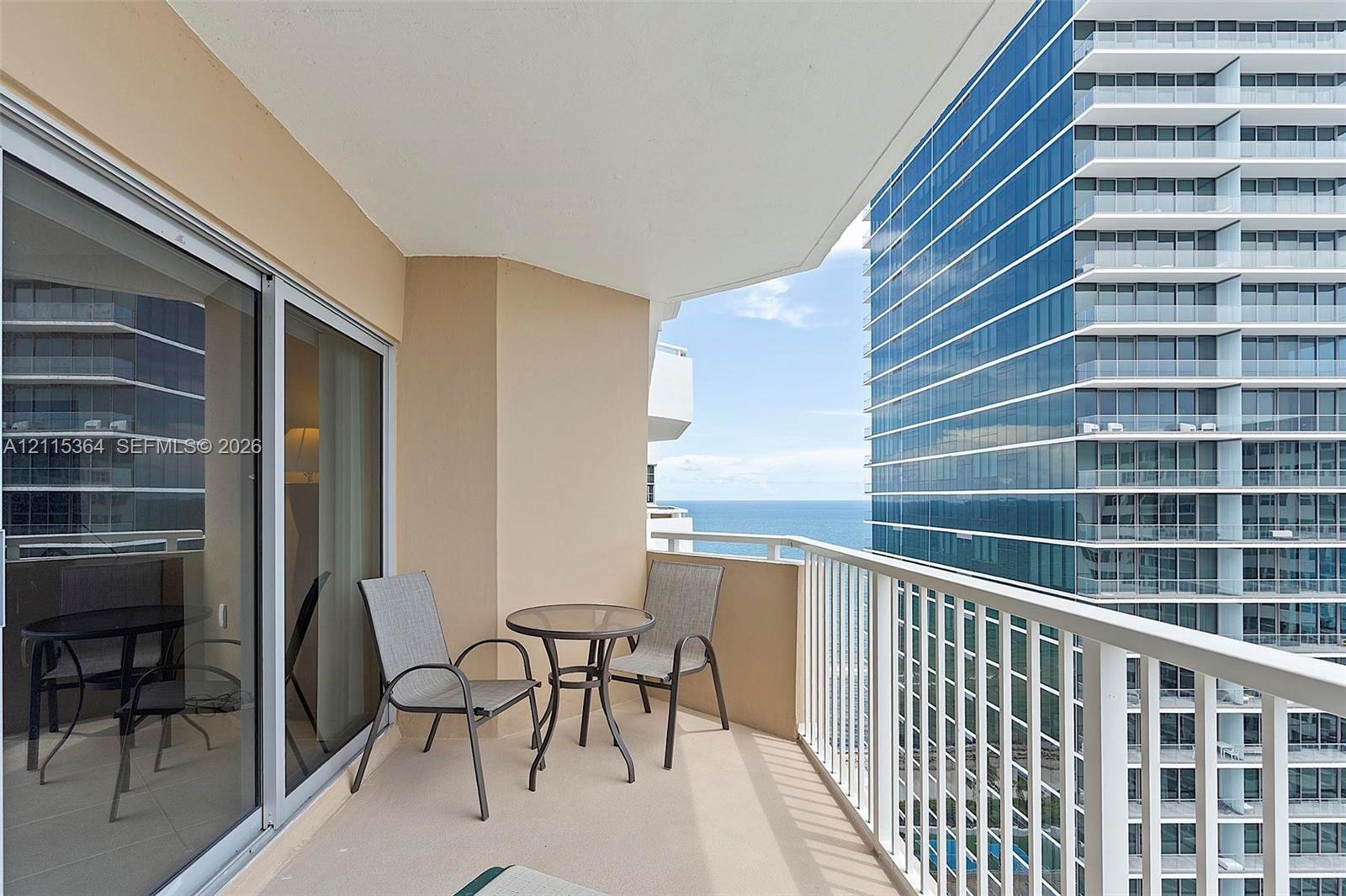 Private balcony featuring white metal railings, concrete flooring, and sliding glass door entry