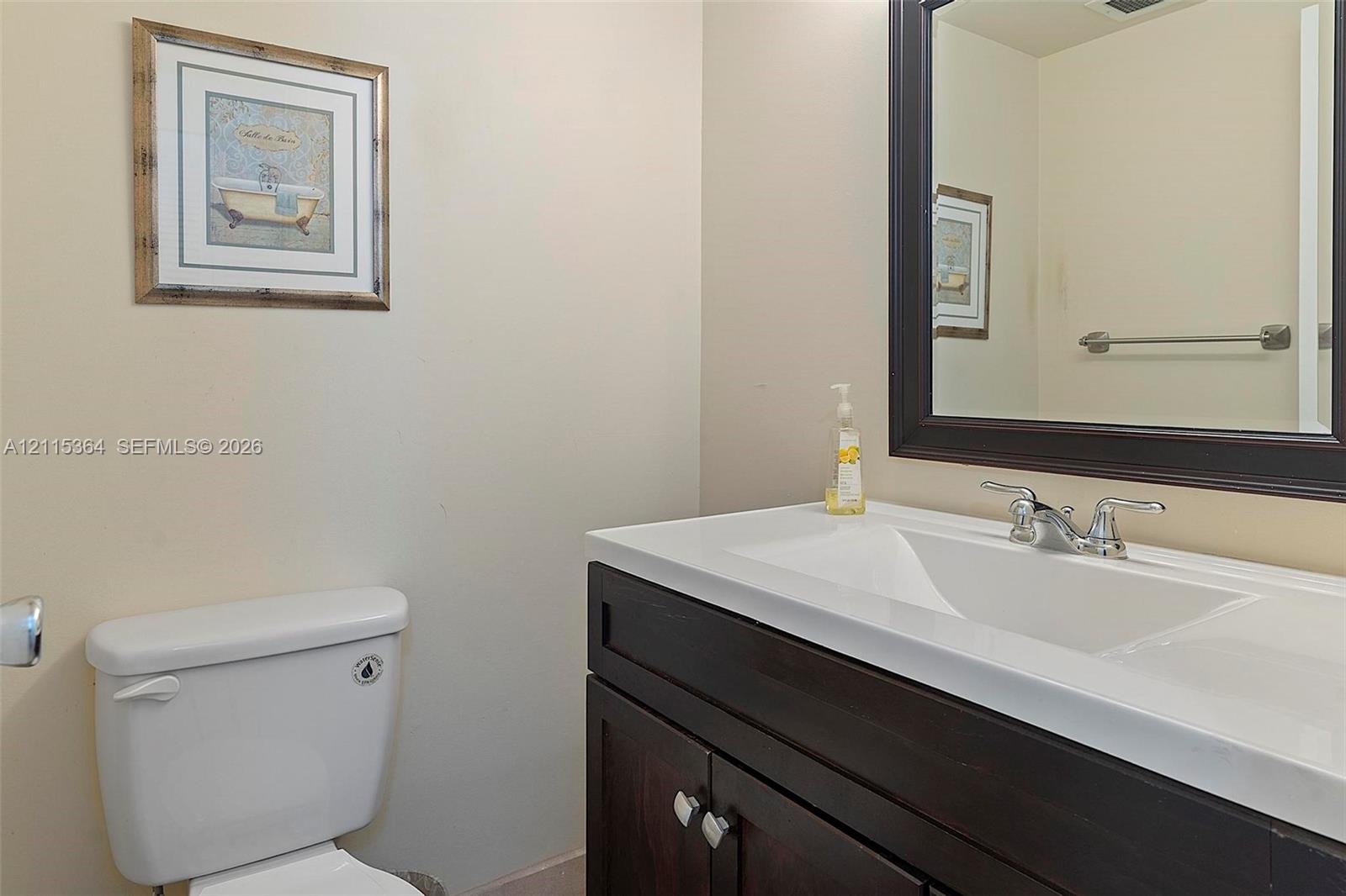 Dark-finish vanity cabinetry with an integrated white sink, polished chrome faucet, and rectangular framed mirror