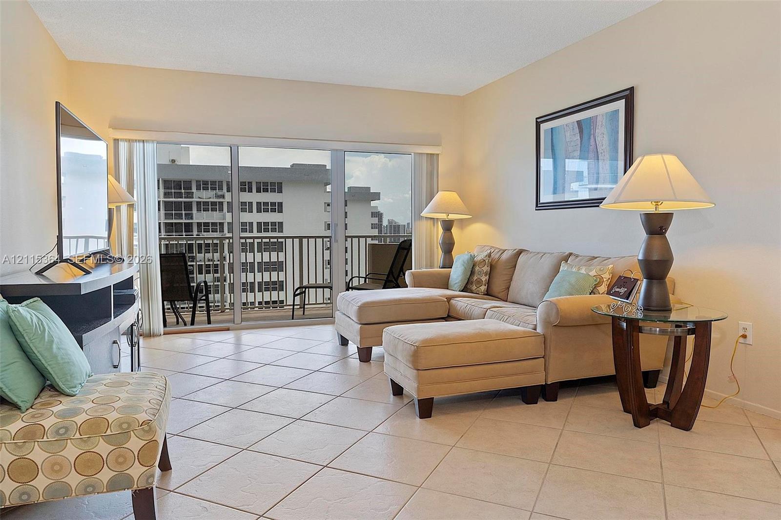 Ceramic tile flooring, neutral wall tones, and large sliding glass doors opening to a private balcony with metal railings