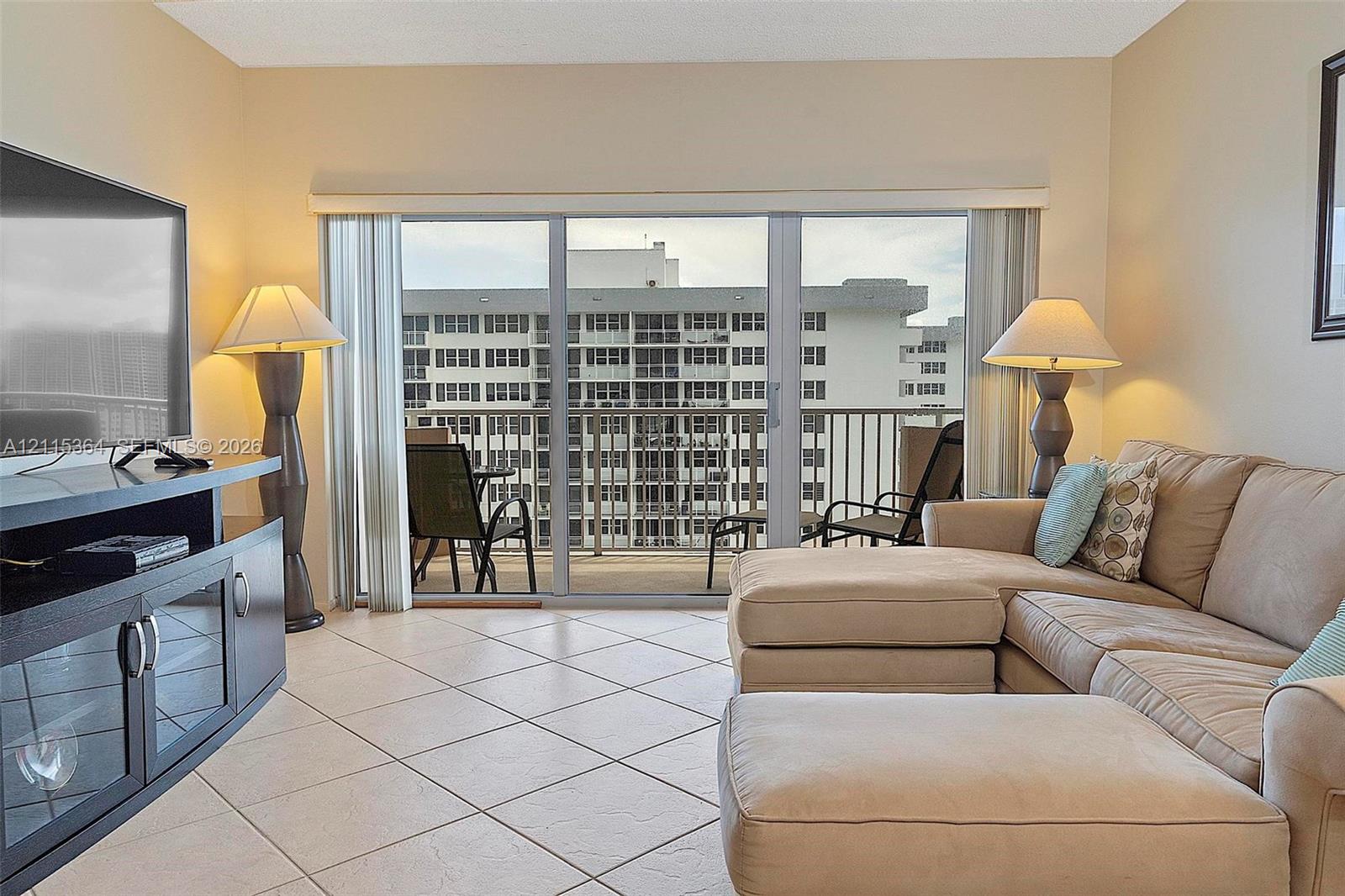 Neutral-toned ceramic tile flooring, sliding glass doors, and a private balcony featuring a metal railing