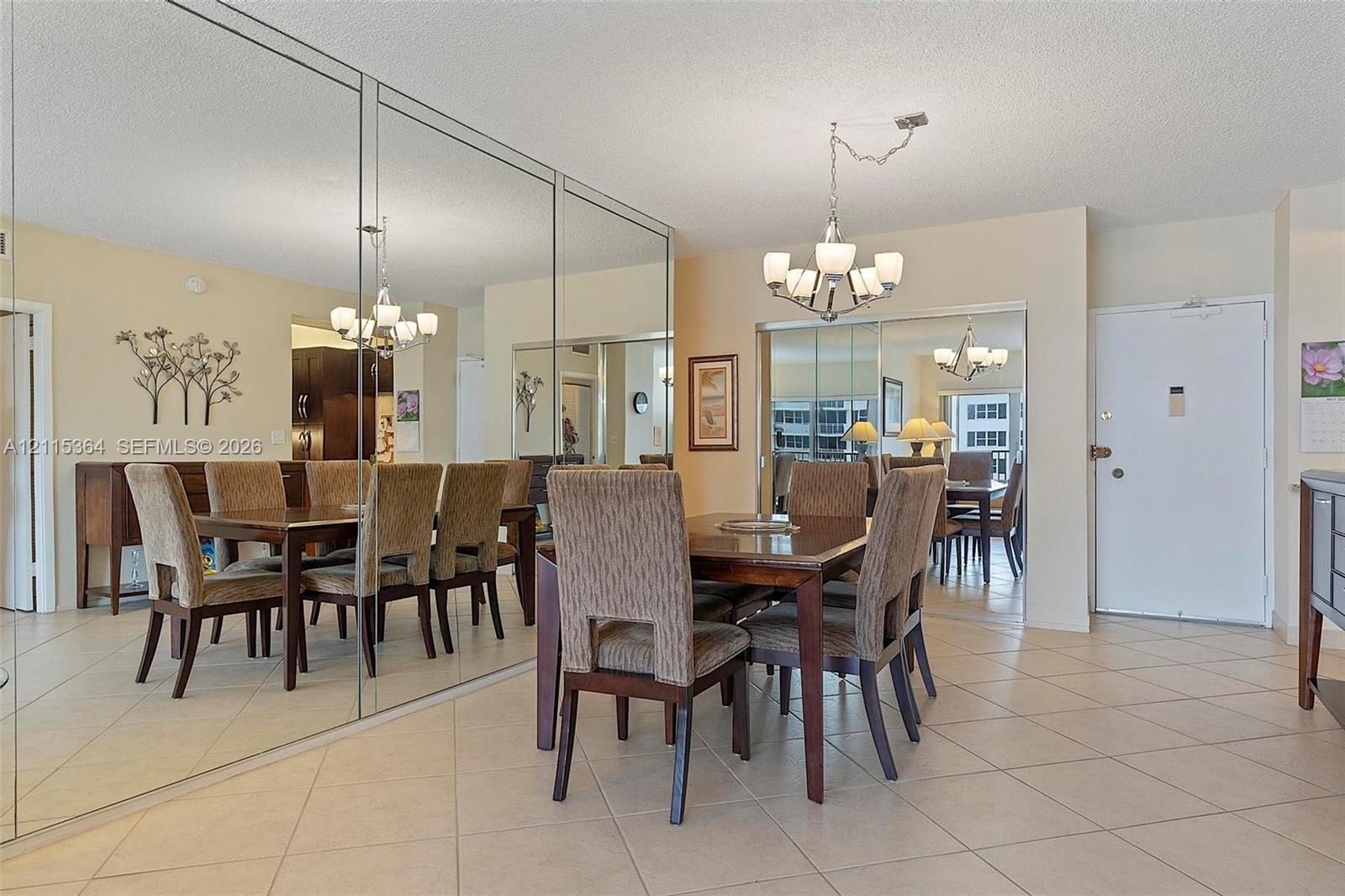 Floor-to-ceiling wall mirror, neutral tile flooring, and multi-light chandelier fixture