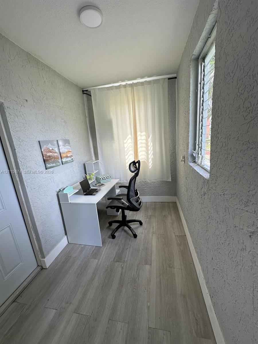 Room featuring textured wall finishes, wood-finish flooring, and a jalousie window