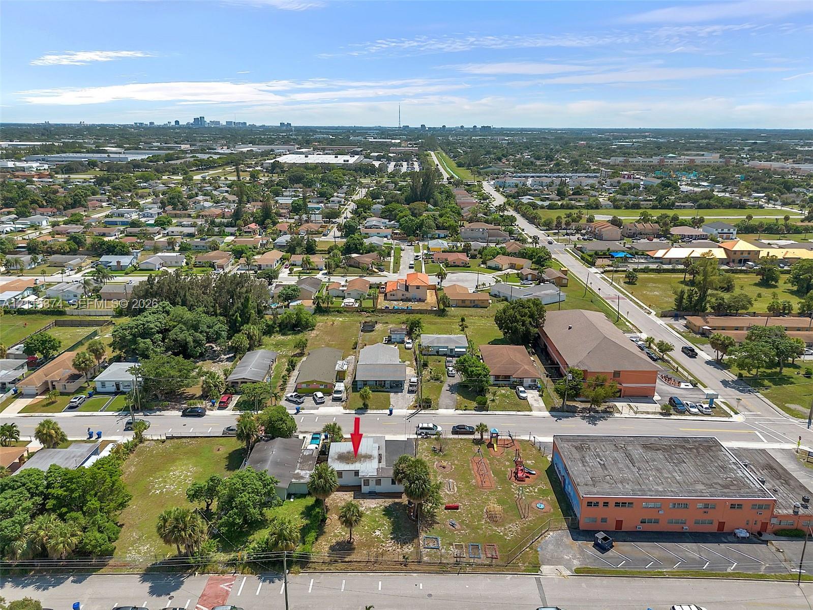 Aerial perspective of property featuring a detached structure, concrete driveway, and established palm trees