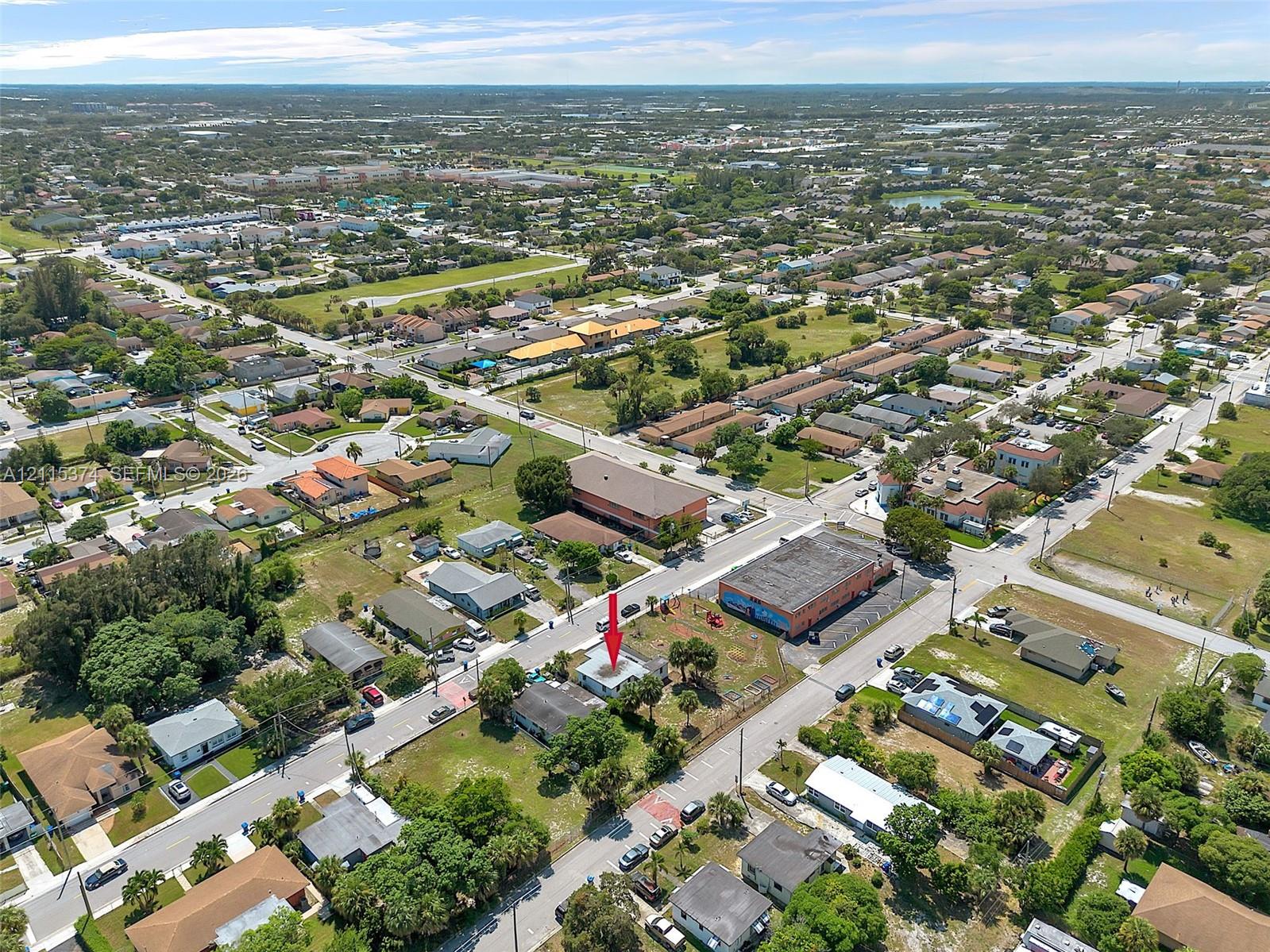 Aerial view of a residential lot situated within an established grid-pattern street layout, featuring mature palm trees and direct paved street access